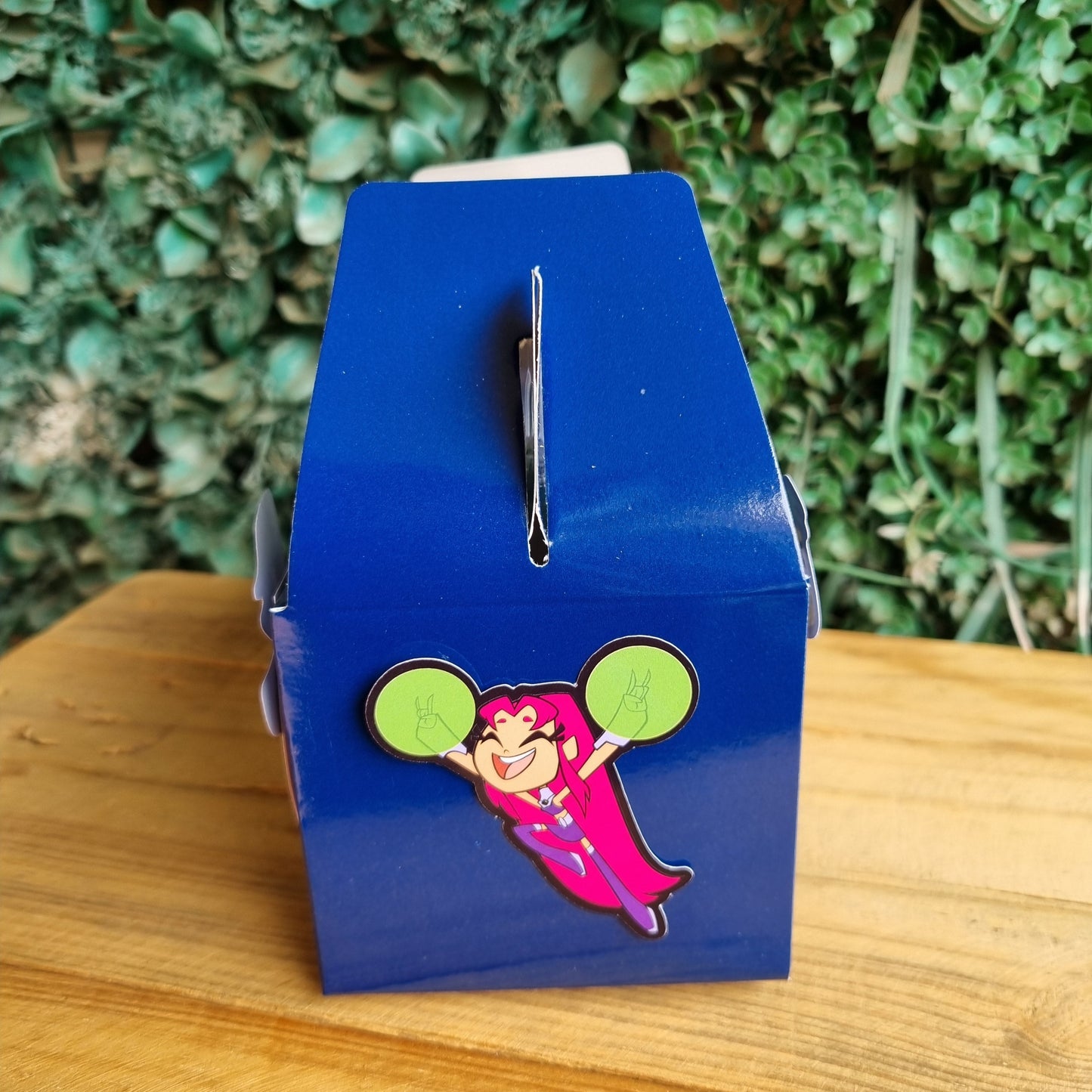Pin with cartoon character on a blue card, placed on grass and wood surface