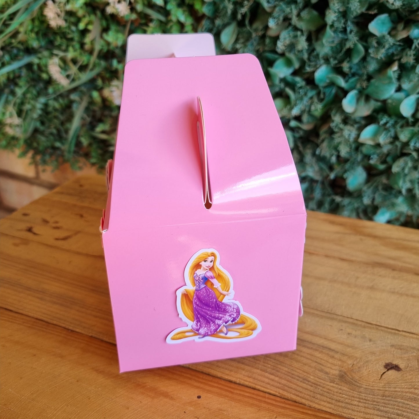 Pink card with a butterfly design on a wooden surface with greenery in the background