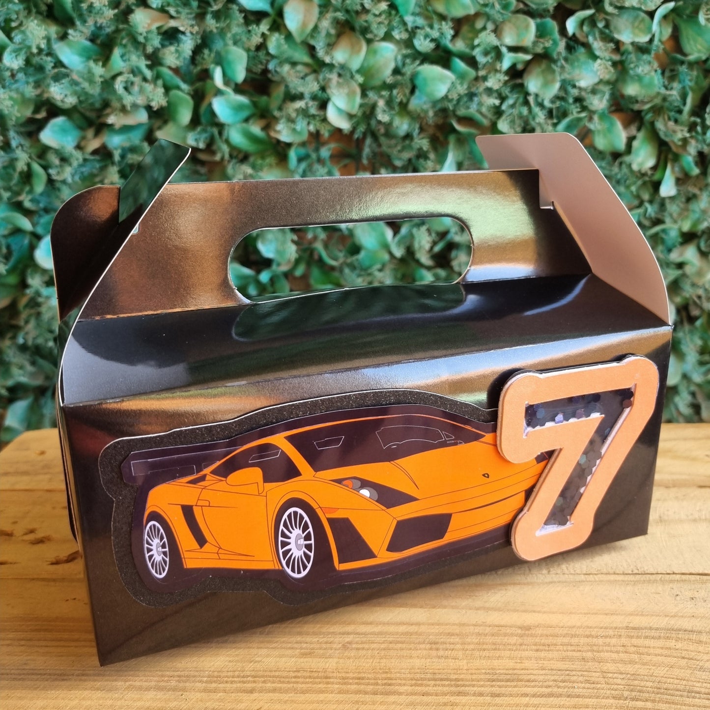 Car-shaped bottle opener on a wooden surface with greenery in the background