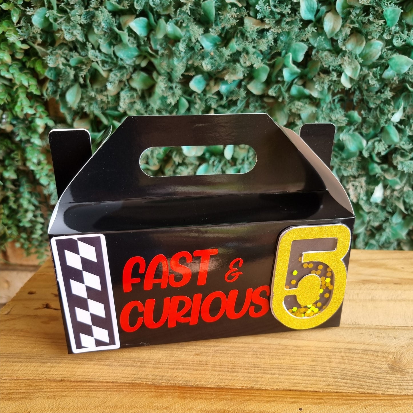 Metallic sign with 'Fast & Curious' text on a textured green and wooden surface