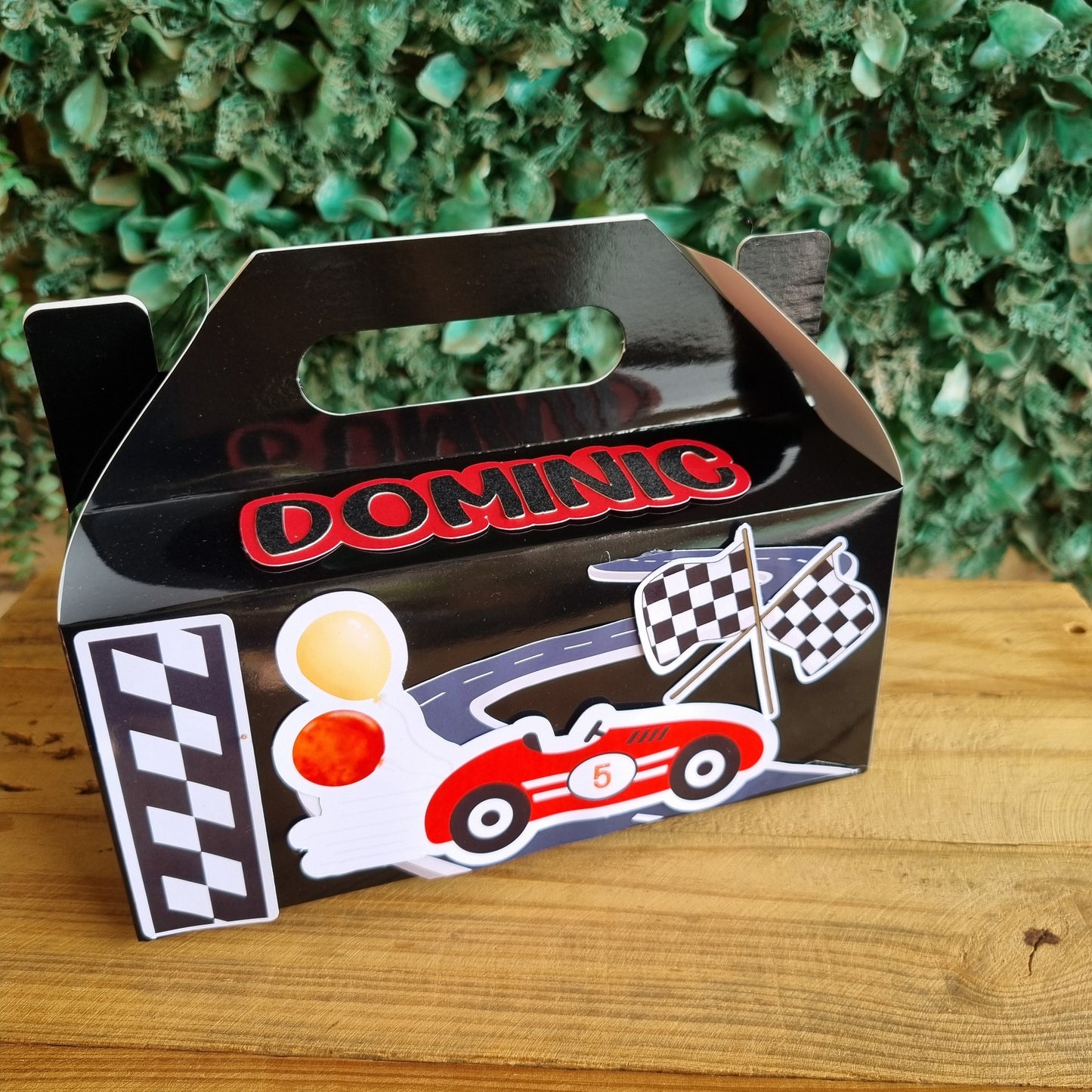Black box with racing car design and 'Dominic' branding on a surface.