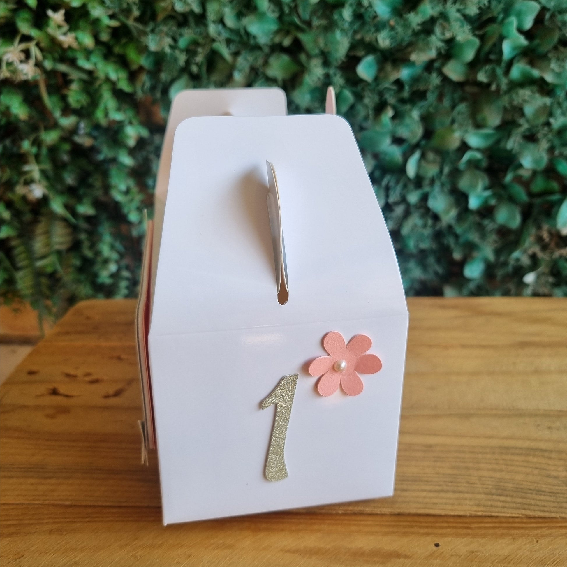Pop-up card with a flower and branch on a wooden surface with greenery in the background