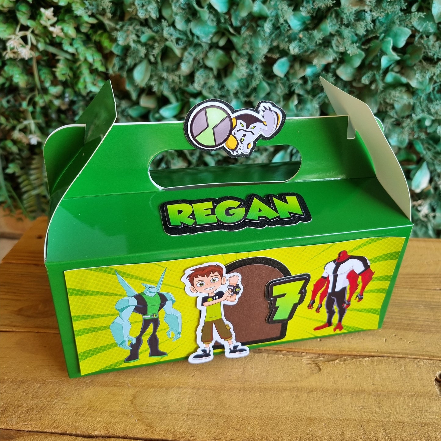 Green and yellow toy box with cartoon characters on a wooden surface and green grass background