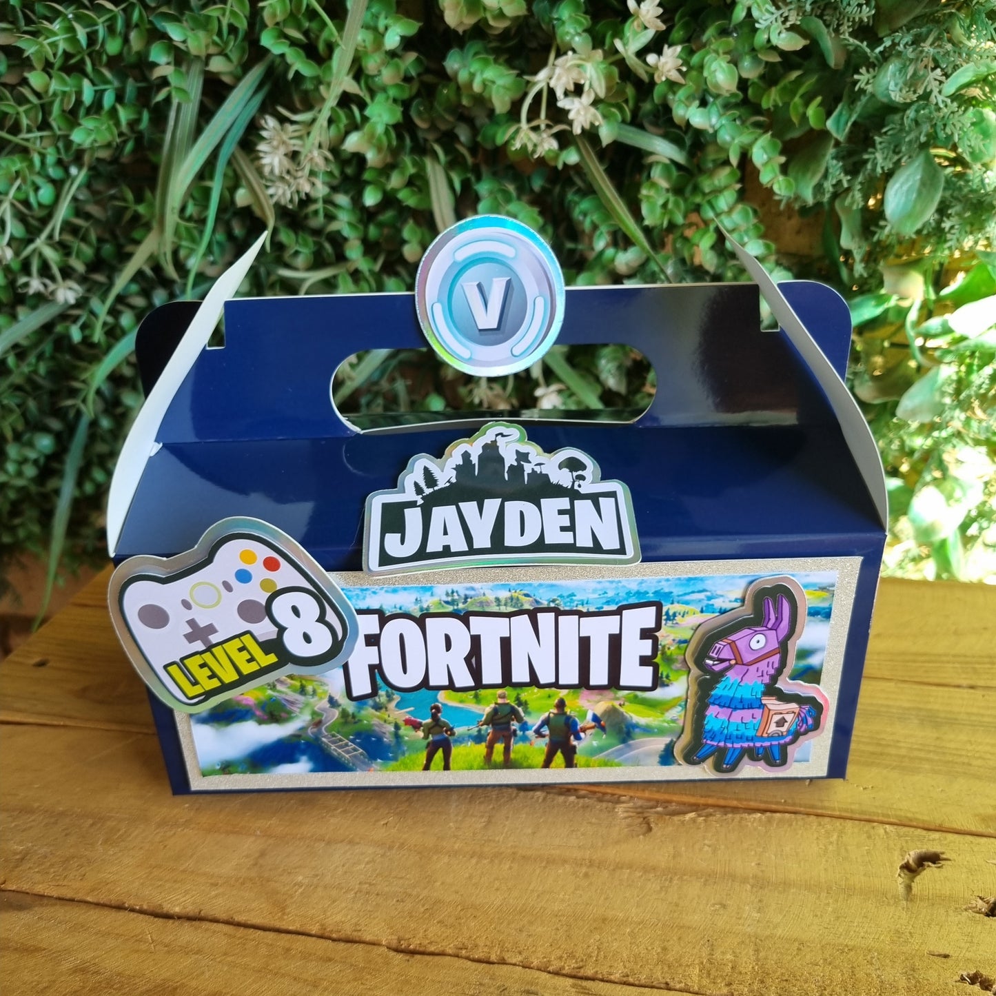 Jayden Fortnite toy with a blue and white design on a wooden surface with greenery.