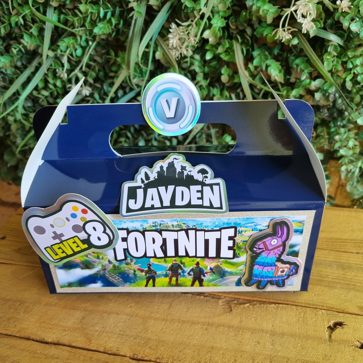 Blue toy with 'Jayden' and 'Fortnite' branding on a wooden surface with grass.