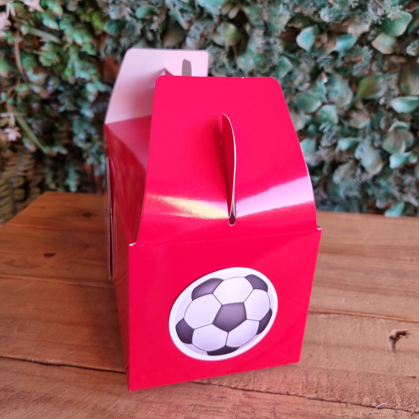 Red card with a soccer ball design on a wooden surface and green grass background