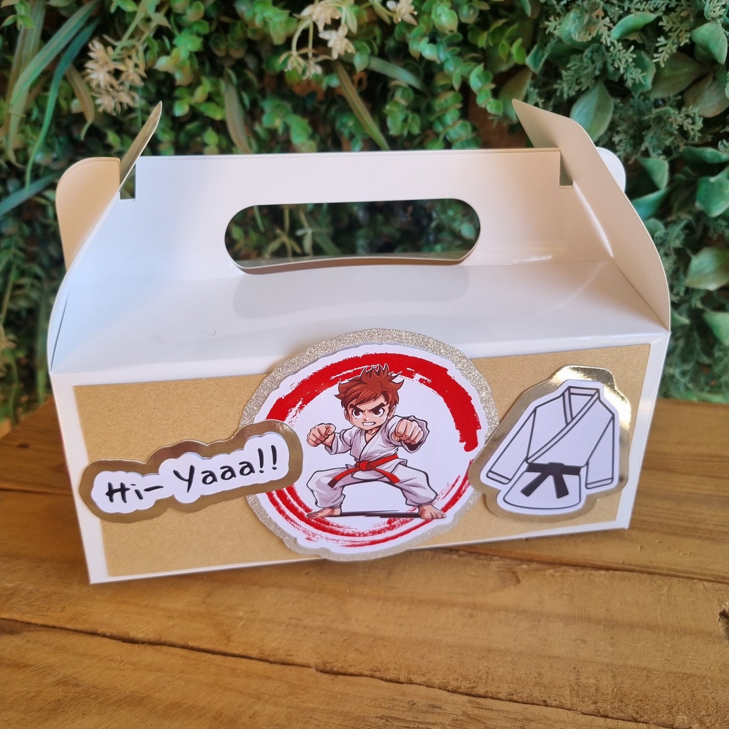 Cardboard box with stickers on a wooden surface and green plants in the background