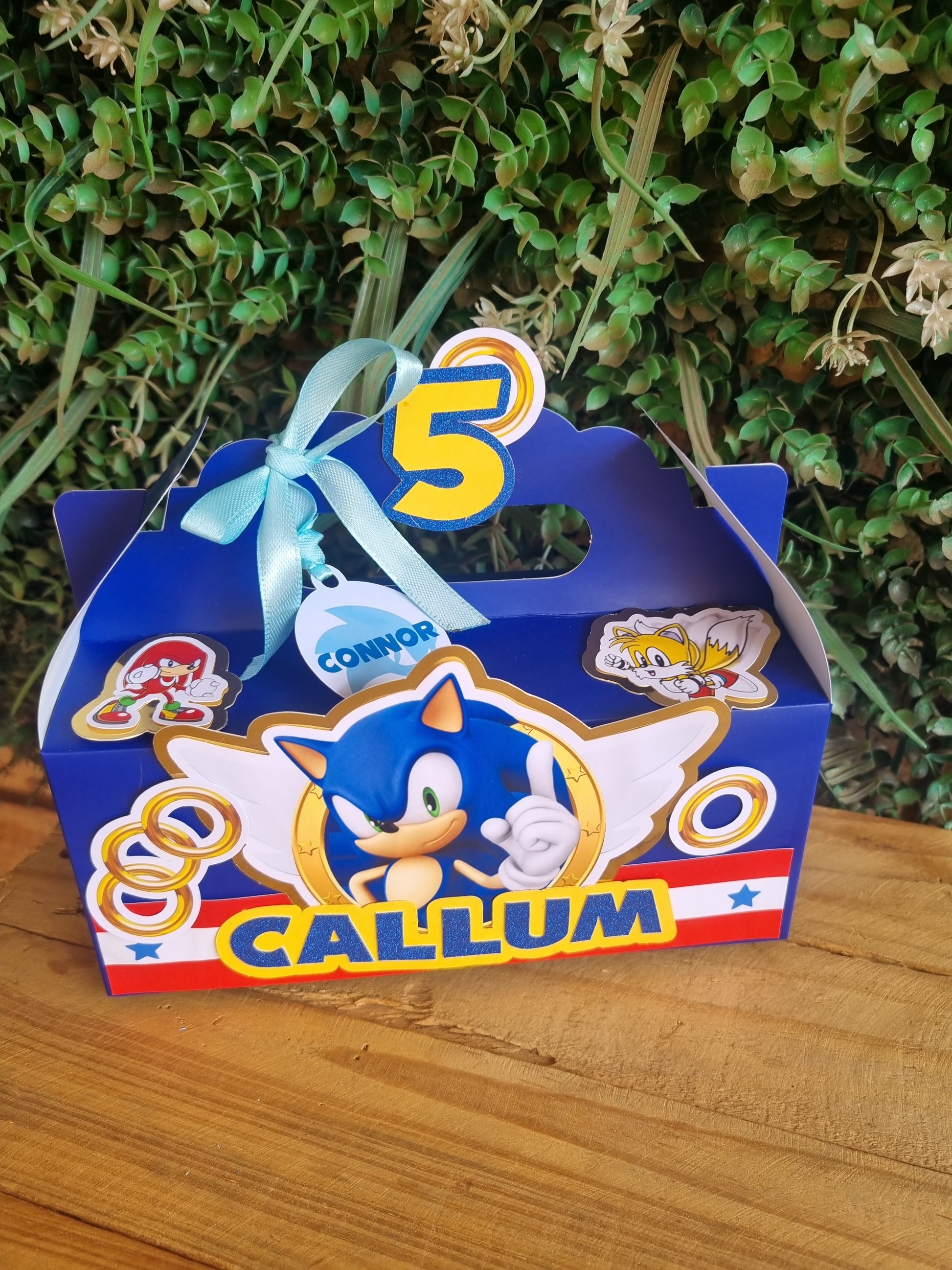 Cartoon character-themed birthday card with blue and red design on a wooden surface.