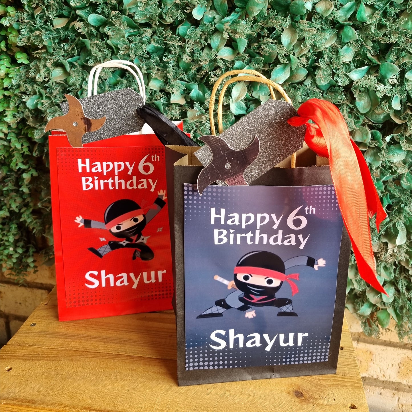 Two birthday cards with a pirate design on a wooden surface with greenery in the background.