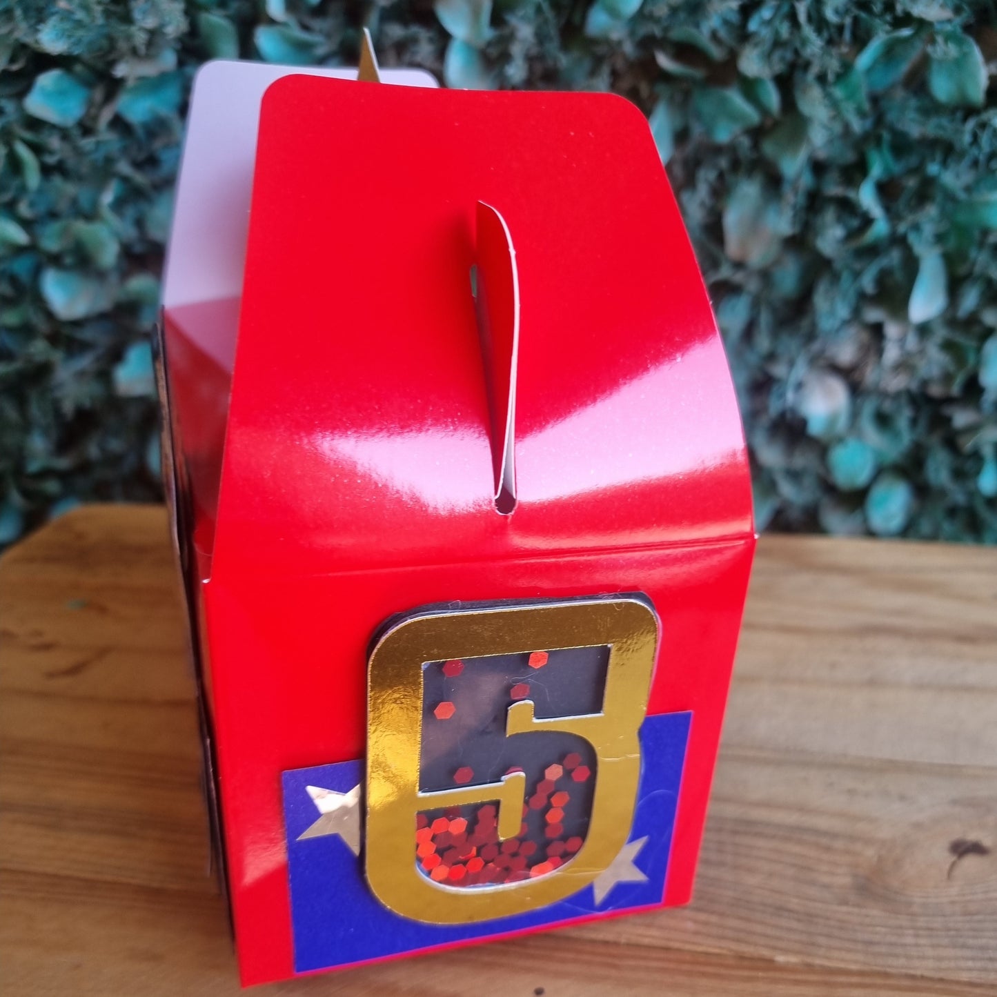 Red and gold object with a star design on a wooden surface