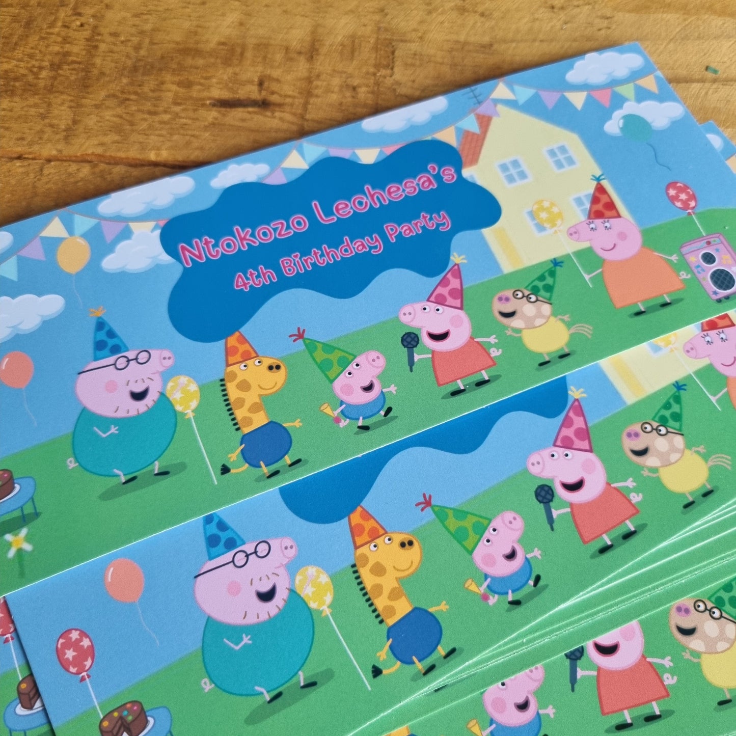 Sheet of Peppa Pig stickers on a wooden surface with greenery in the background
