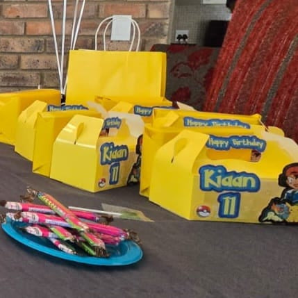 Yellow party favor bags with 'Happy Birthday Kidaan 11' text on a table.
