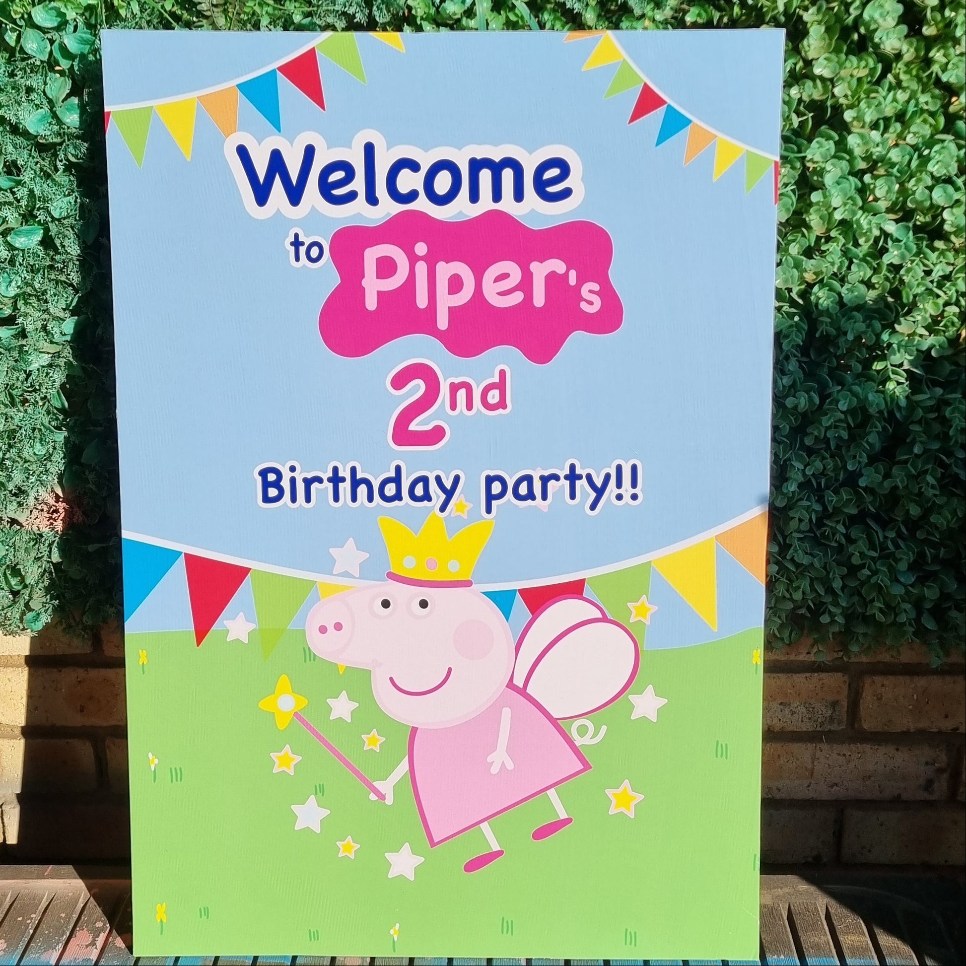 Birthday party sign with cartoon character on a green bush