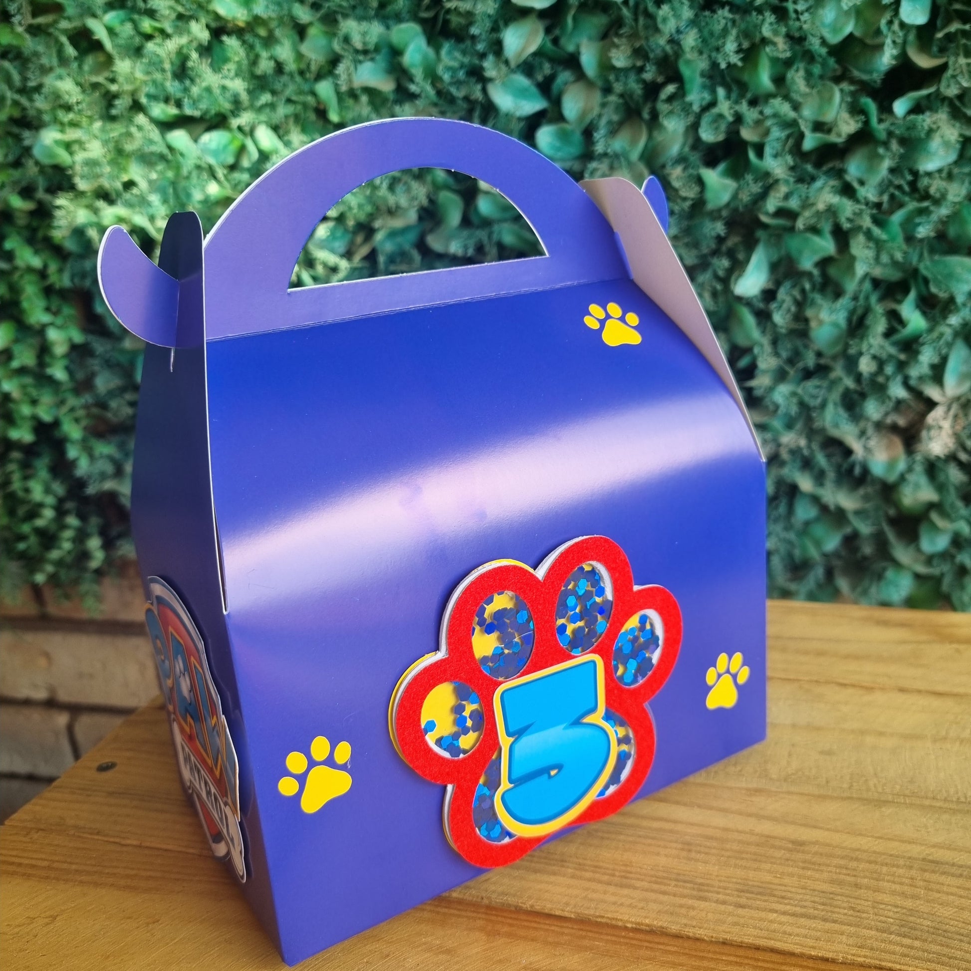 Blue mug with colorful paw design on a wooden surface and green background