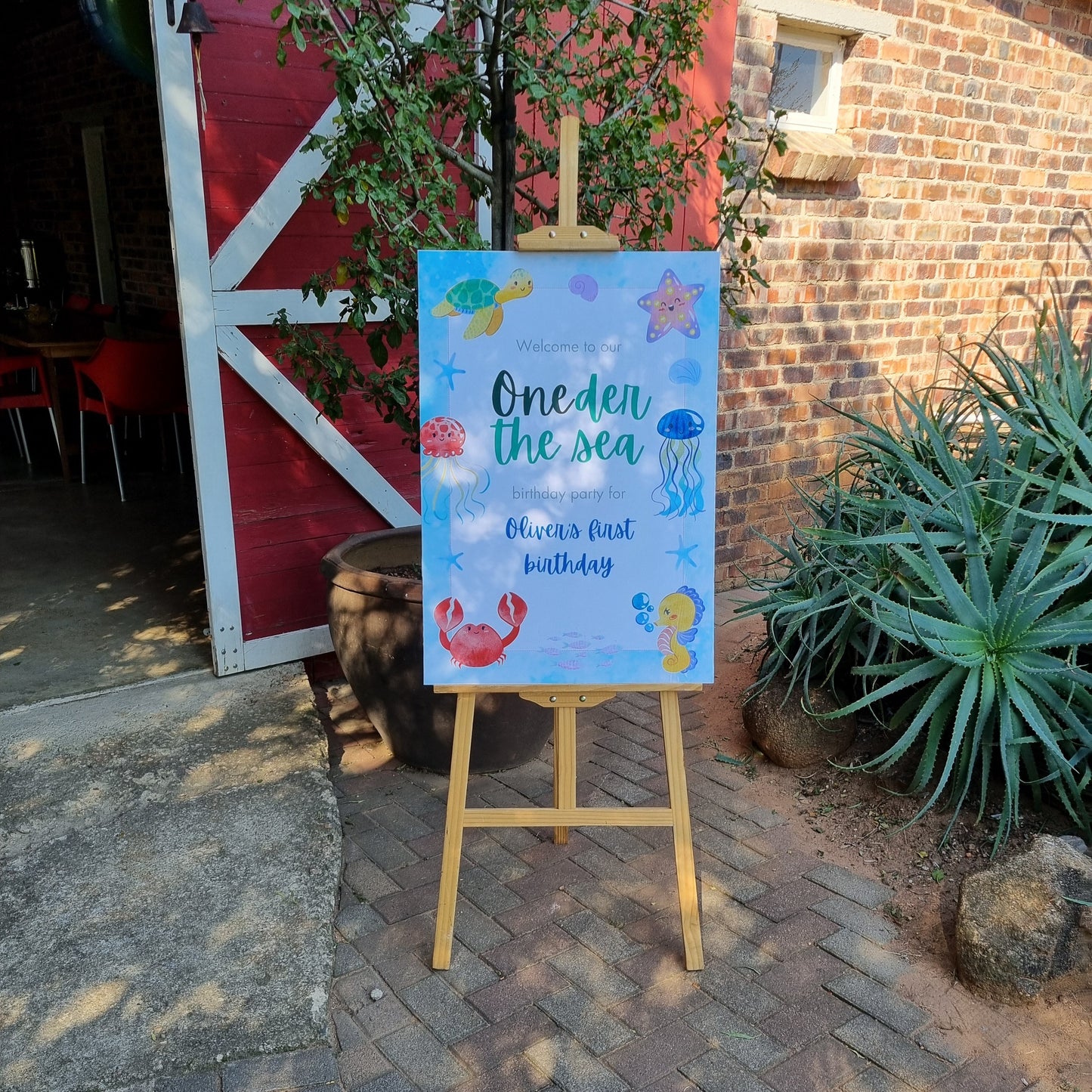 Decorative sign with text and illustrations on a wooden stand outdoors.