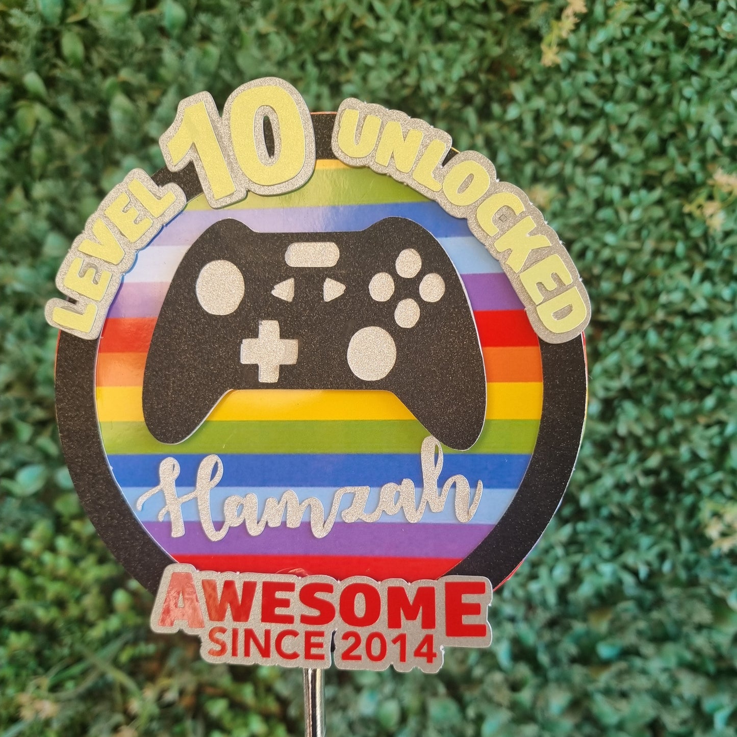 Colorful badge with gaming controller design on a grass background
