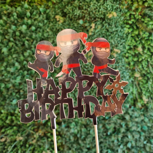 Metallic 'Happy Birthday' cake topper with cartoon characters on a green grass background