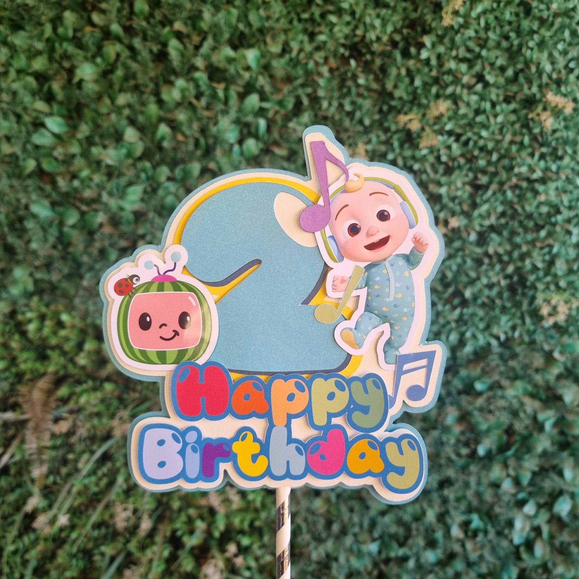 Colorful birthday cake topper with cartoon characters on a green grass background