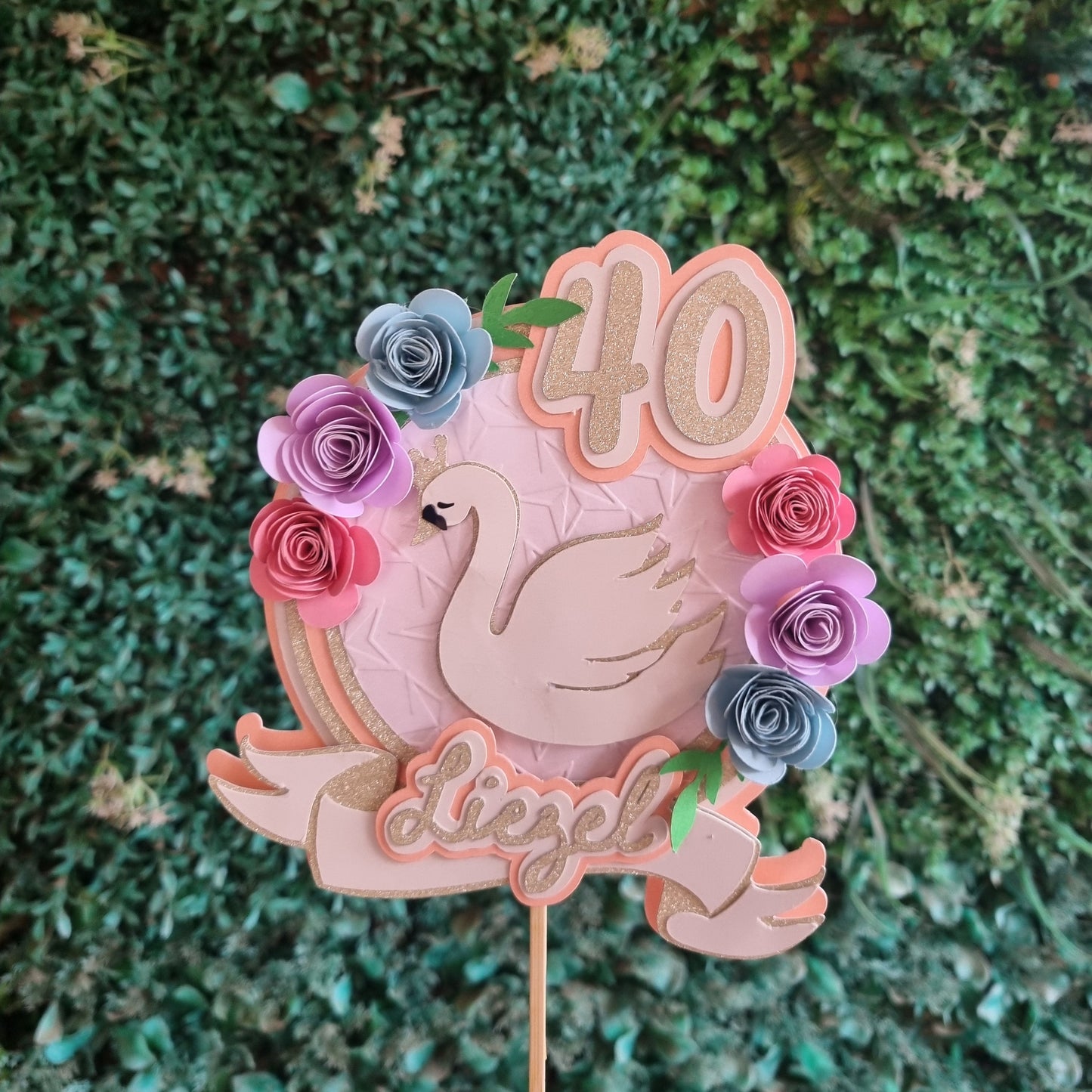 Decorative cake topper with flowers and text on a green grass background