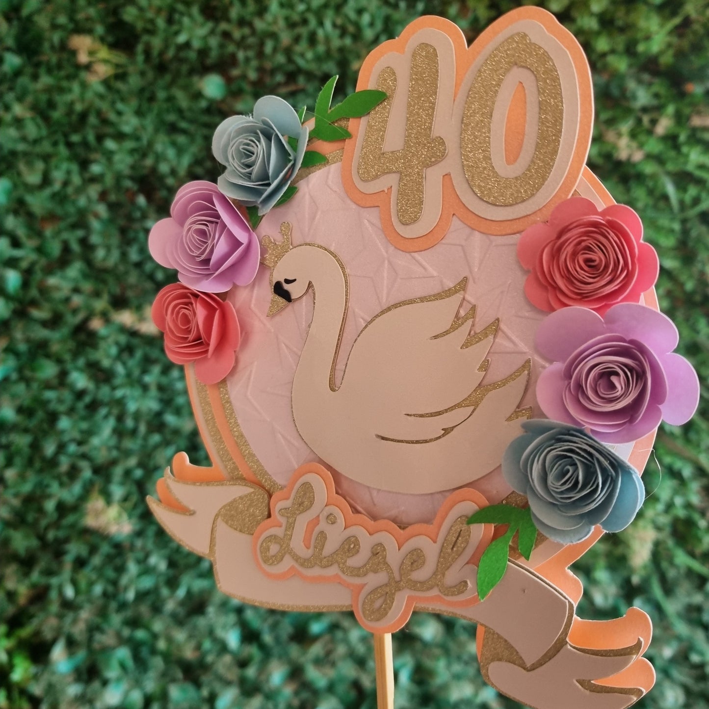 Decorative cake topper with flowers and '40' on a green grass background