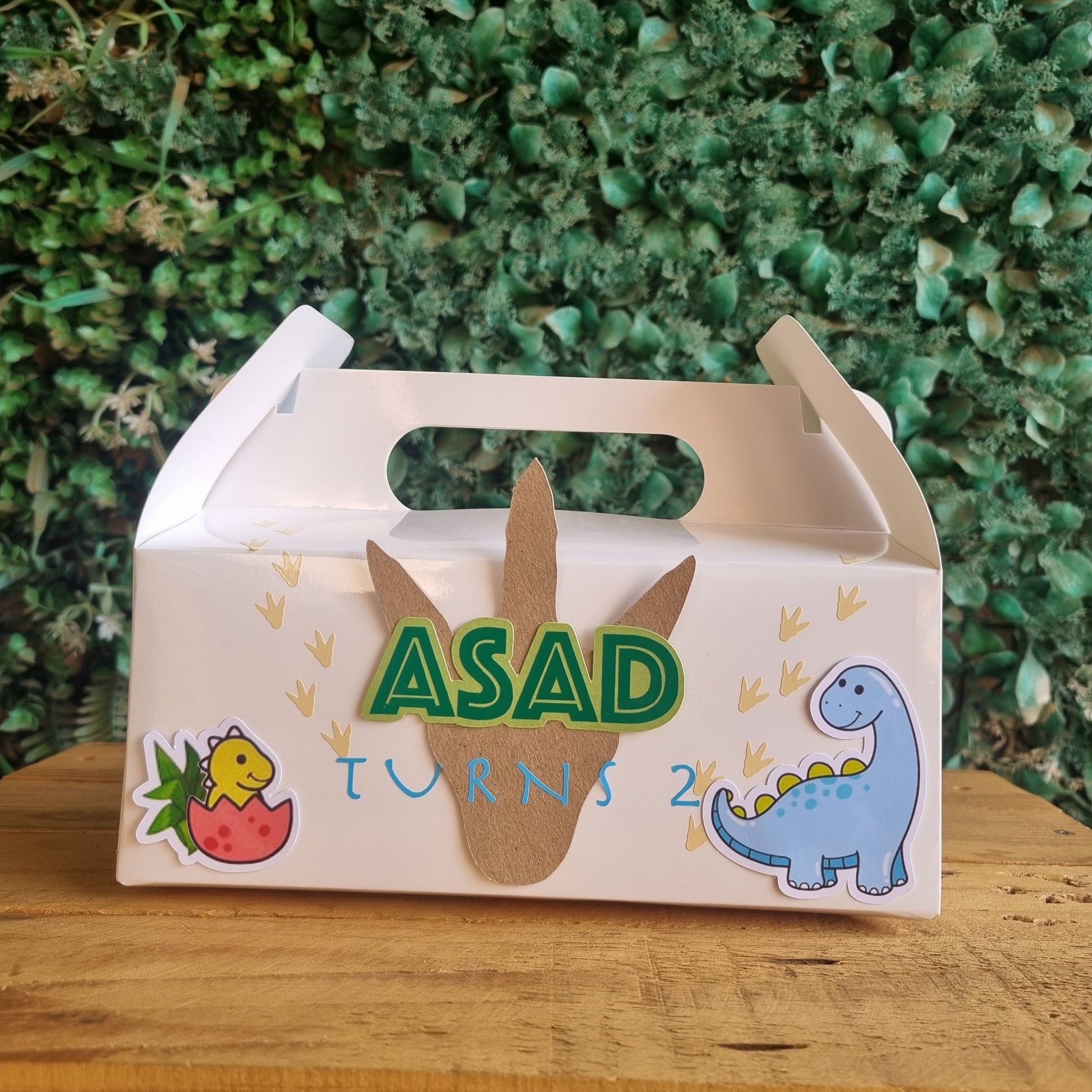 Children's step stool with dinosaur design and 'ASAD' text on a wooden surface.