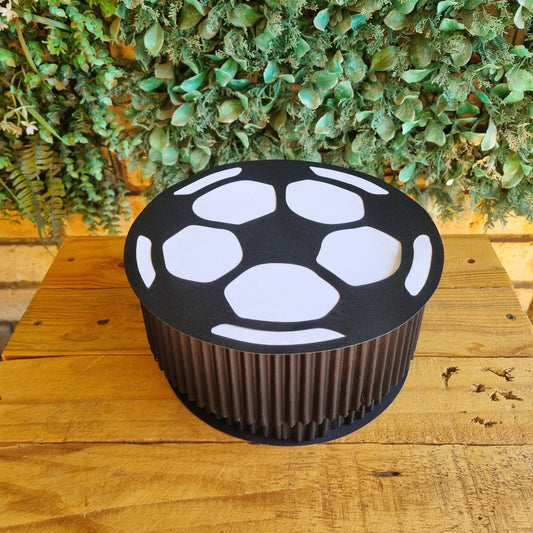 Black and white outdoor light fixture on a wooden wall with green foliage in the background