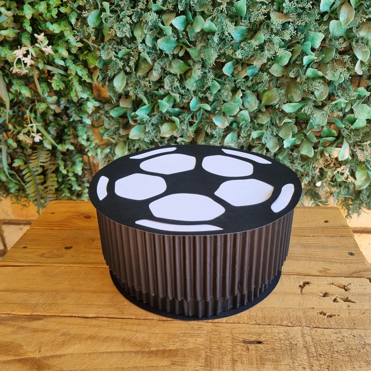 Black and white outdoor light fixture on a wooden post with green foliage in the background