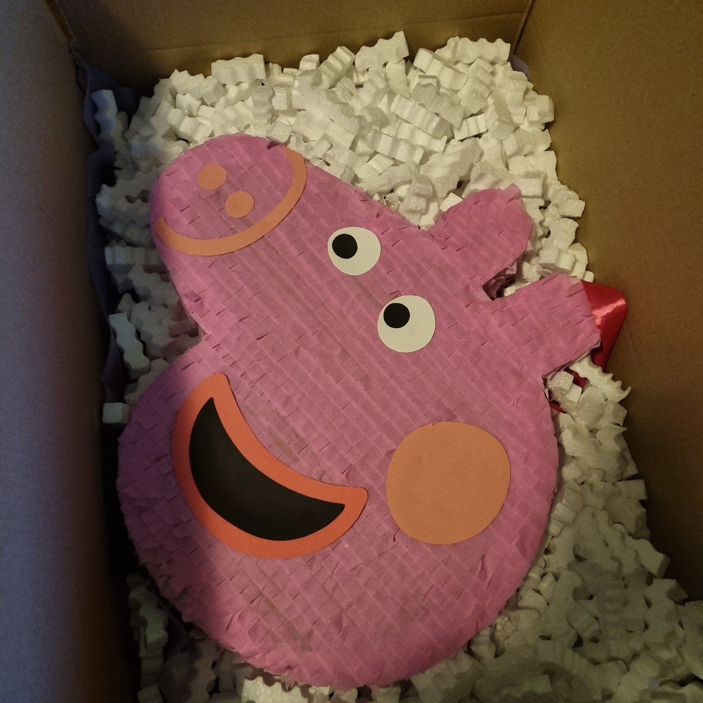 Pink pig-shaped piñata in a box with bubble wrap