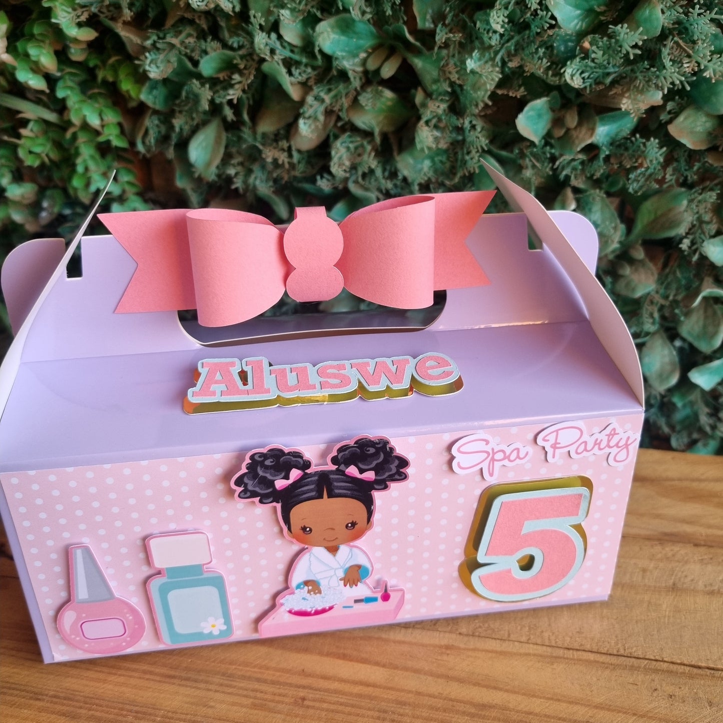Pink hair bow with packaging featuring cartoon characters on a wooden surface and green foliage background