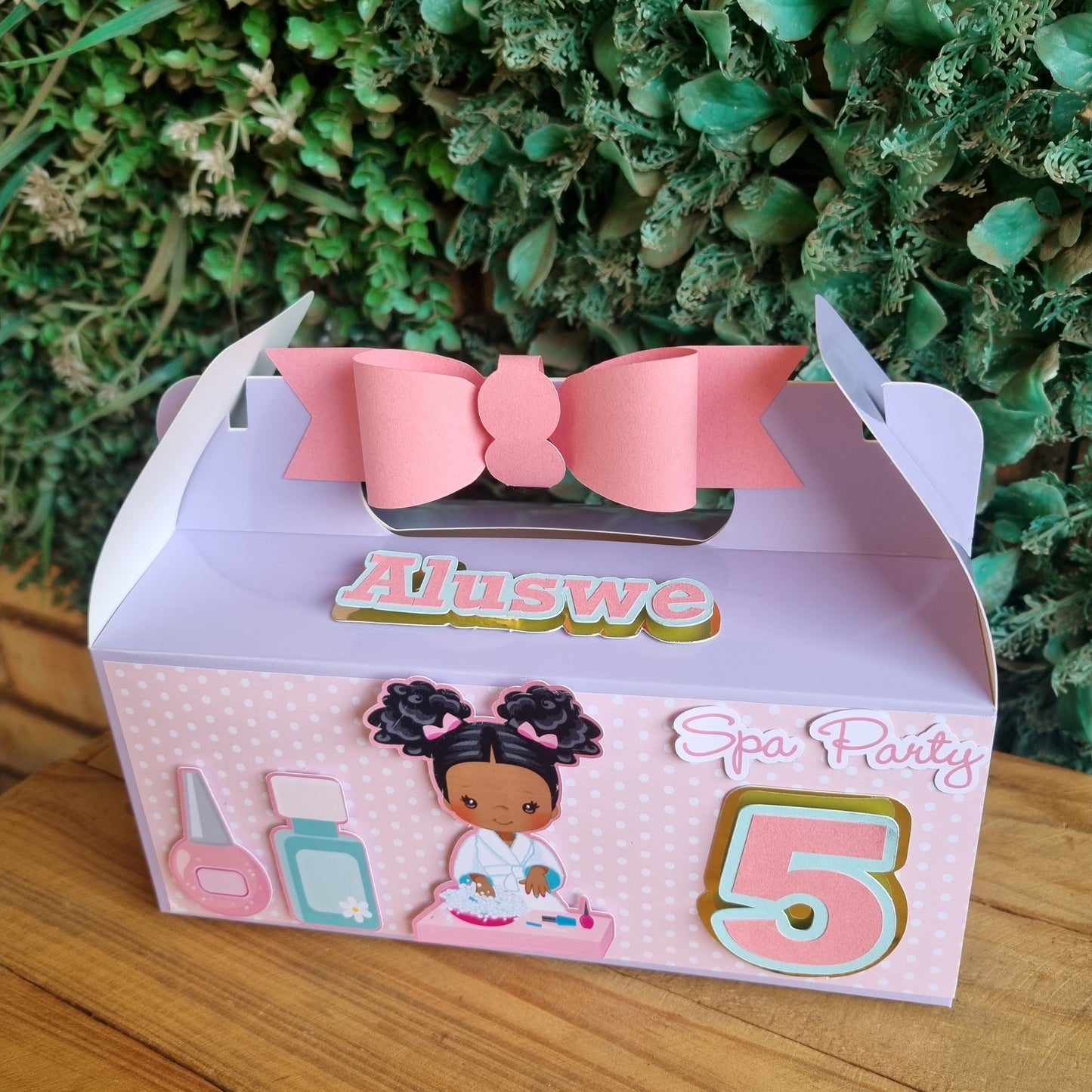 Gift box with pink bow and decorative elements on a wooden surface
