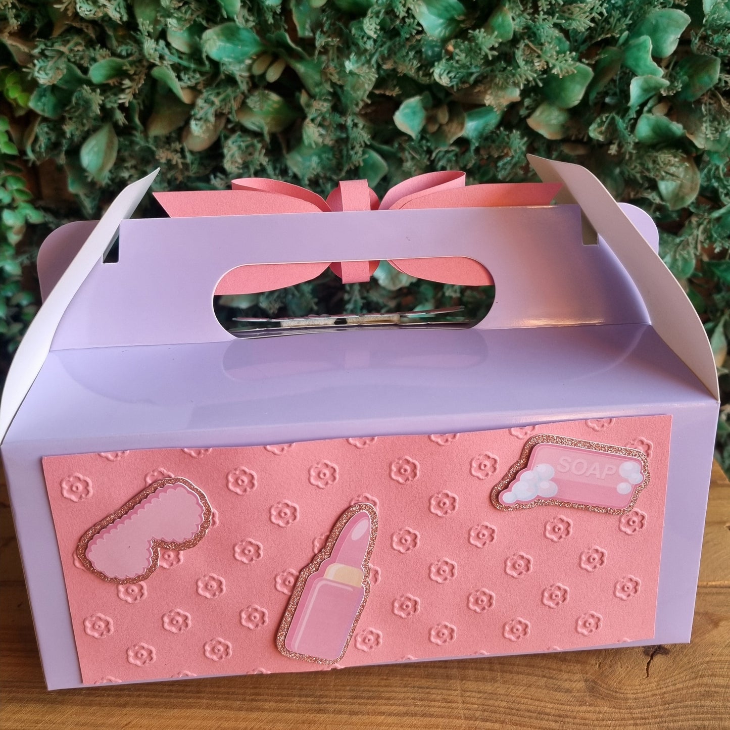 Pink and purple gift box with heart designs on a wooden surface