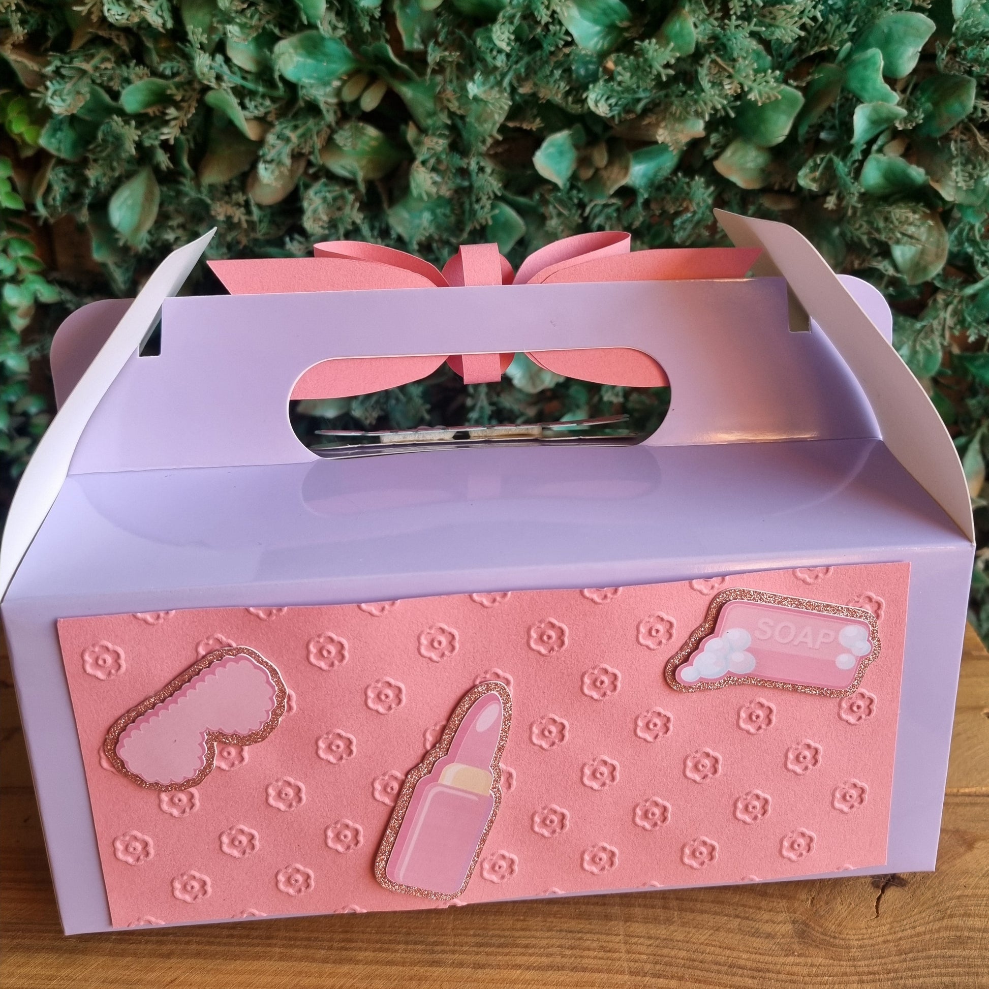 Pink and purple gift box with heart designs on a wooden surface