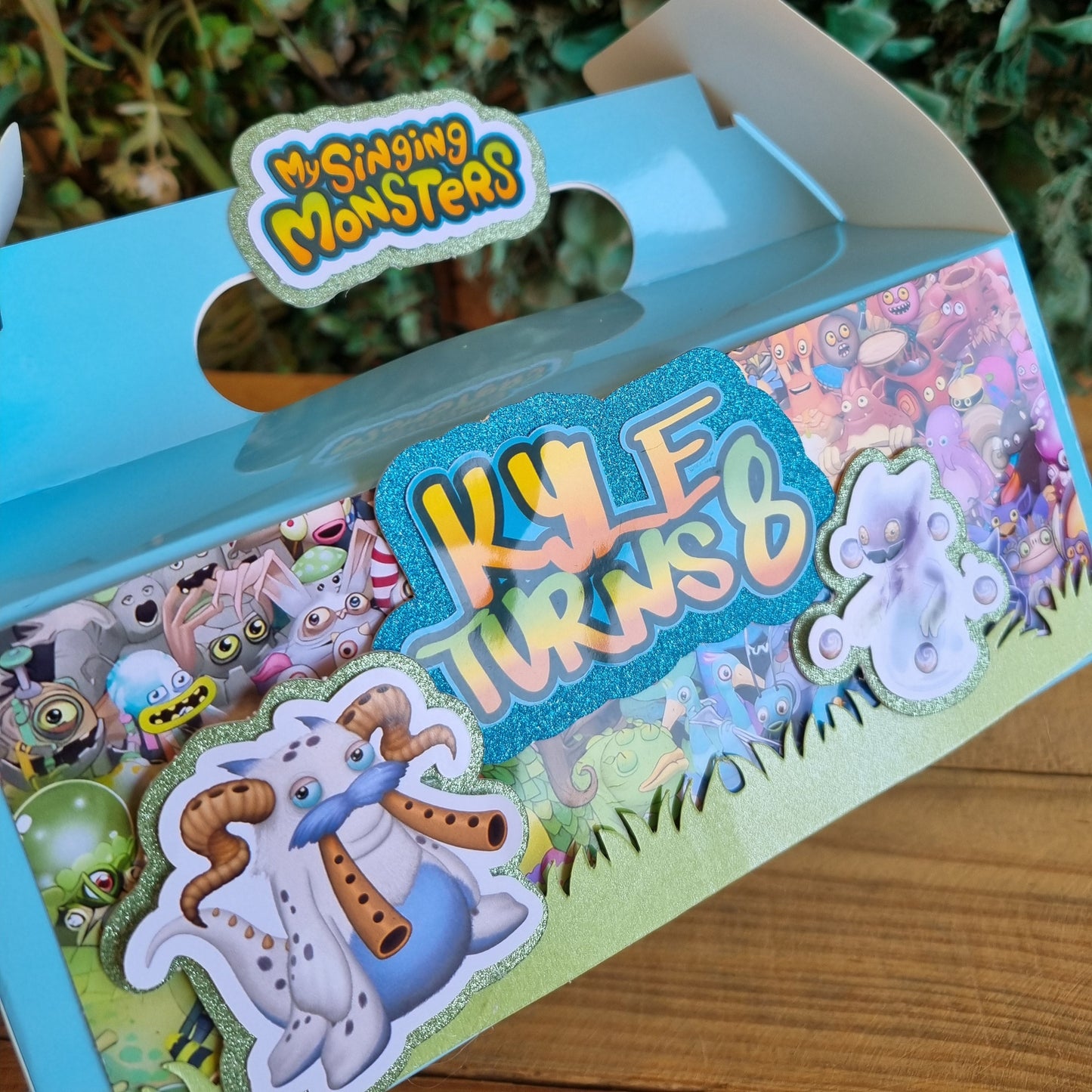 Children's toy with colorful design and 'Shining Monsters' branding on a natural background