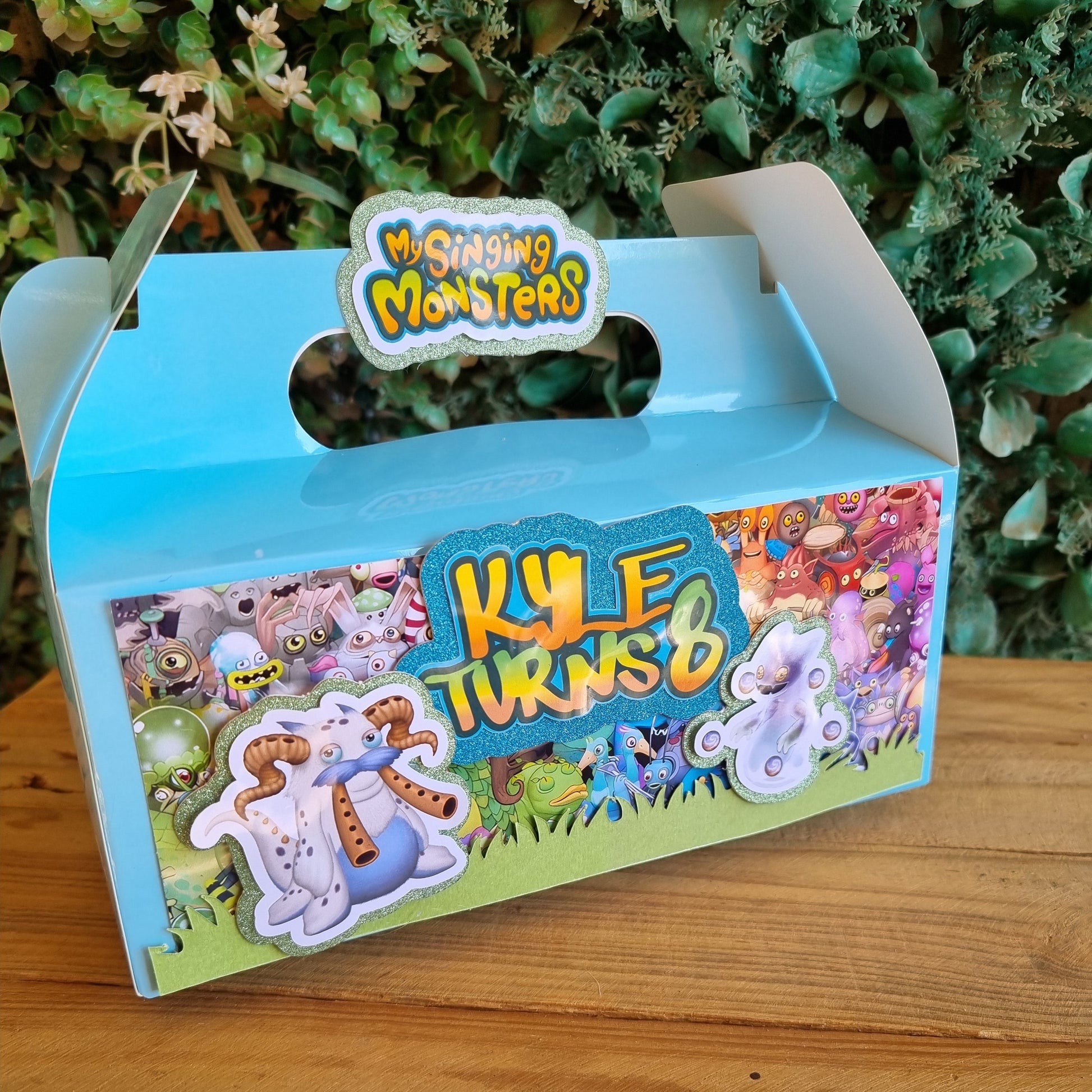 Colorful toy packaging with cartoon characters on a wooden surface and green plants in the background