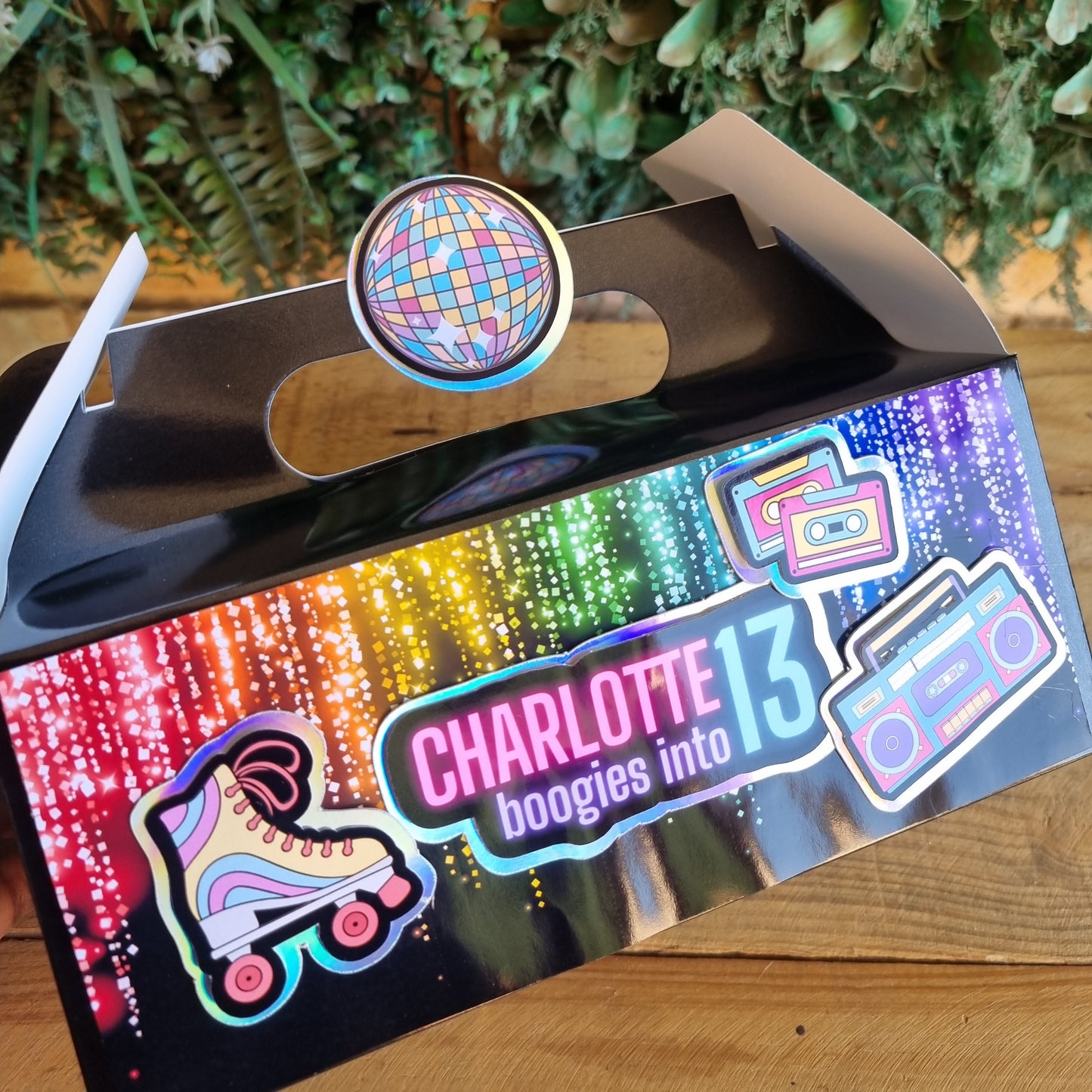 Phone case with disco ball design and 'Charlotte 13' branding on a colorful box.