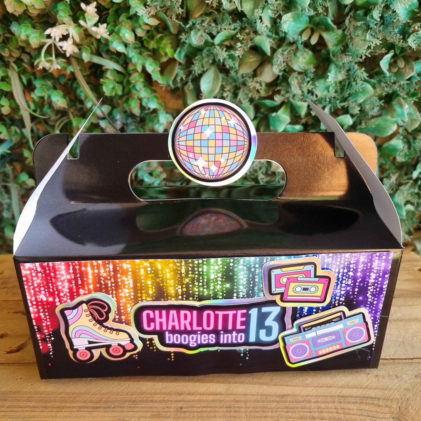 Decorative item with a colorful disco ball design on a wooden surface and green foliage background