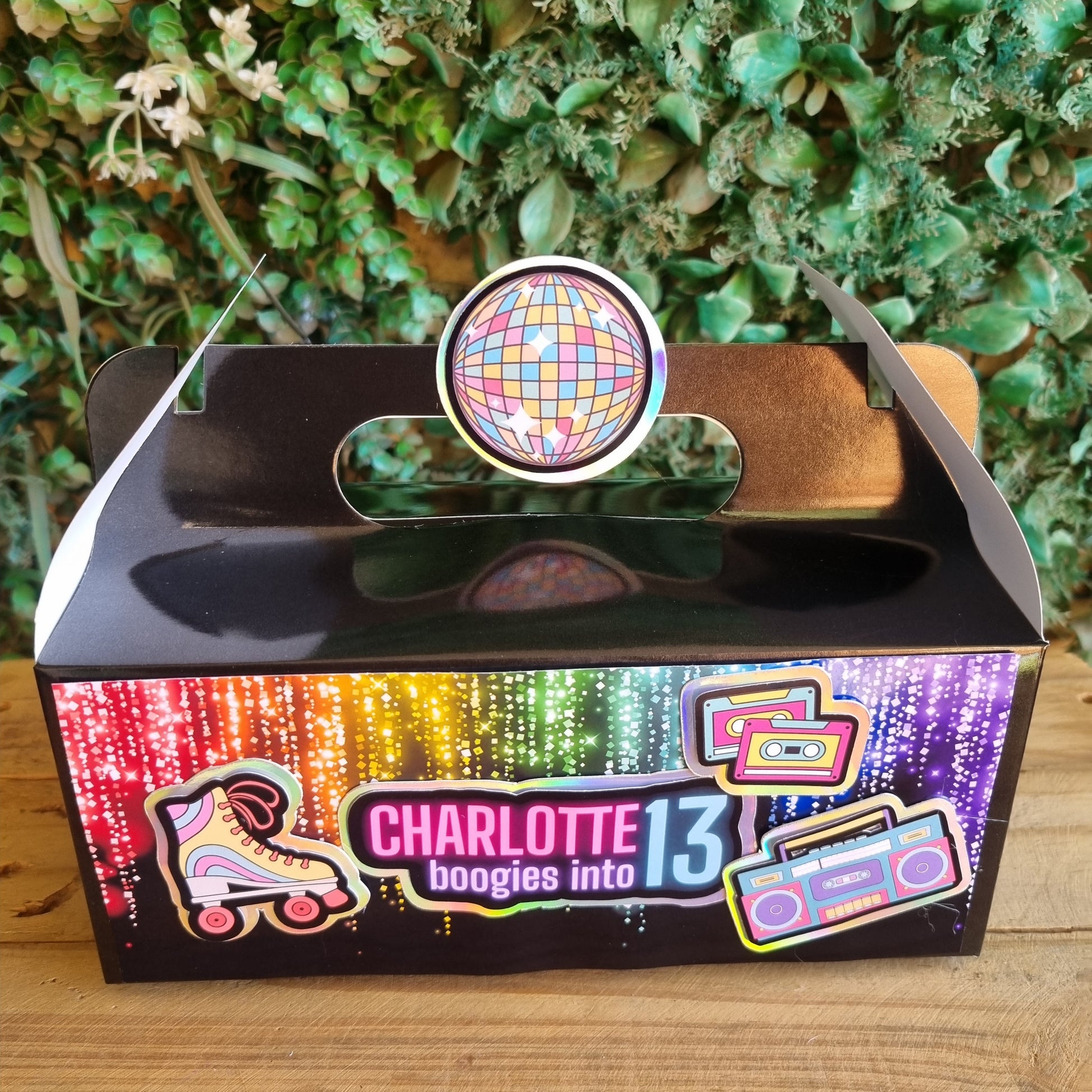 Decorative item with a colorful disco ball design on a wooden surface and green foliage background