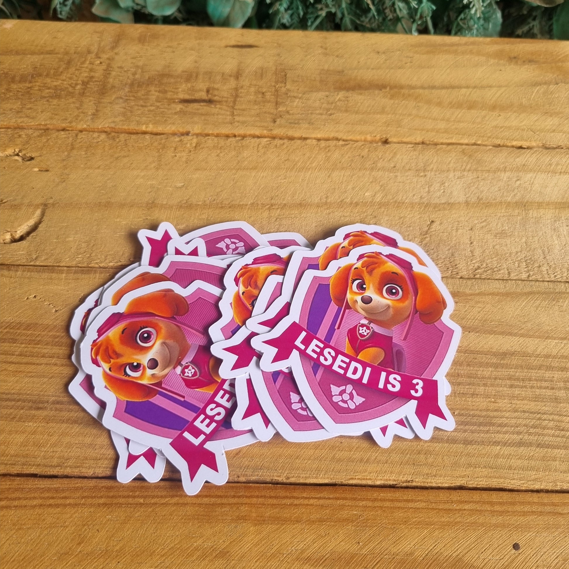 Two pink stickers with a cartoon character on a wooden surface