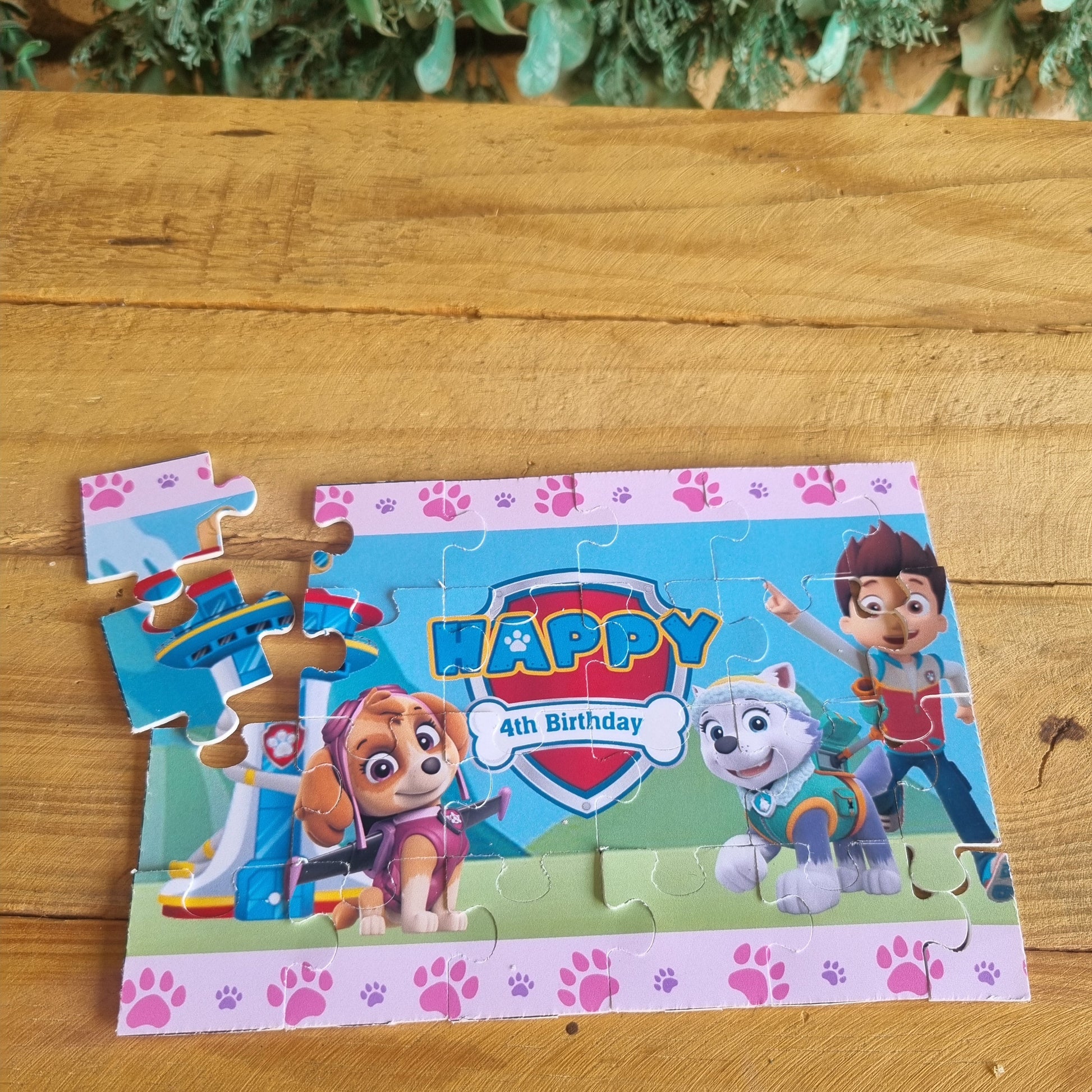 Paw Patrol birthday puzzle on a wooden surface with greenery