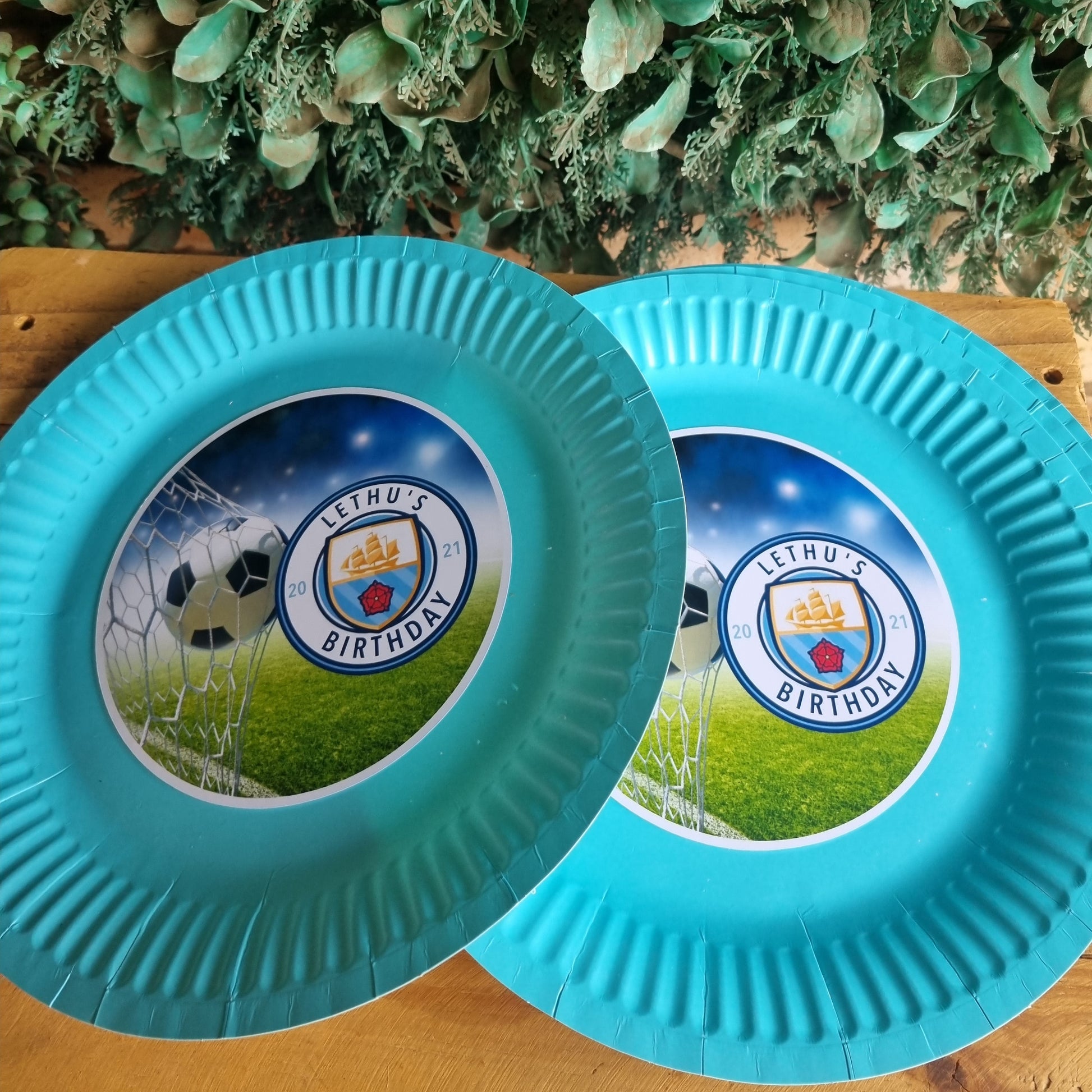 Two blue frisbees with a sports team logo on a wooden surface.