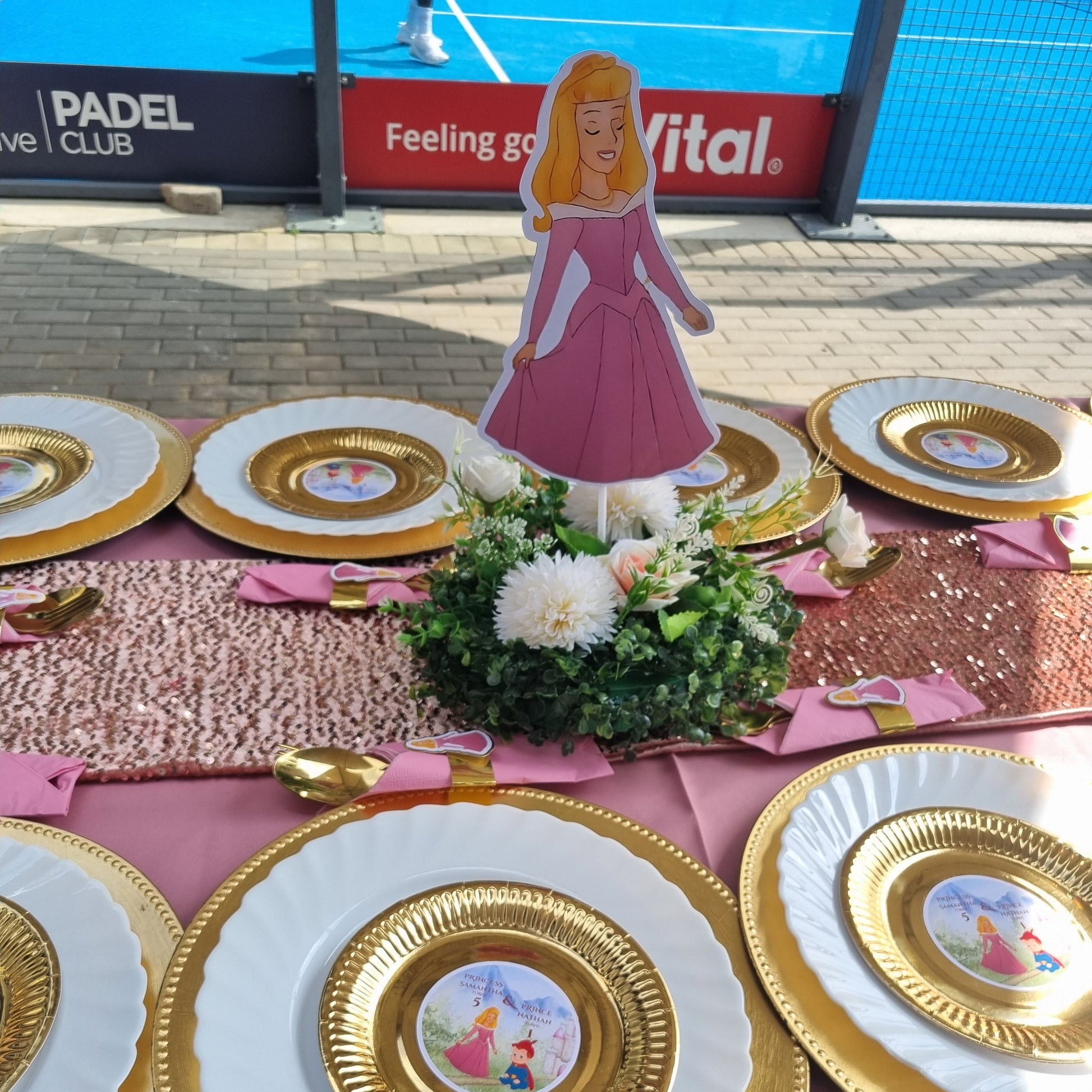 Decorative wall with gold and white plates, flowers, and a pink sign.