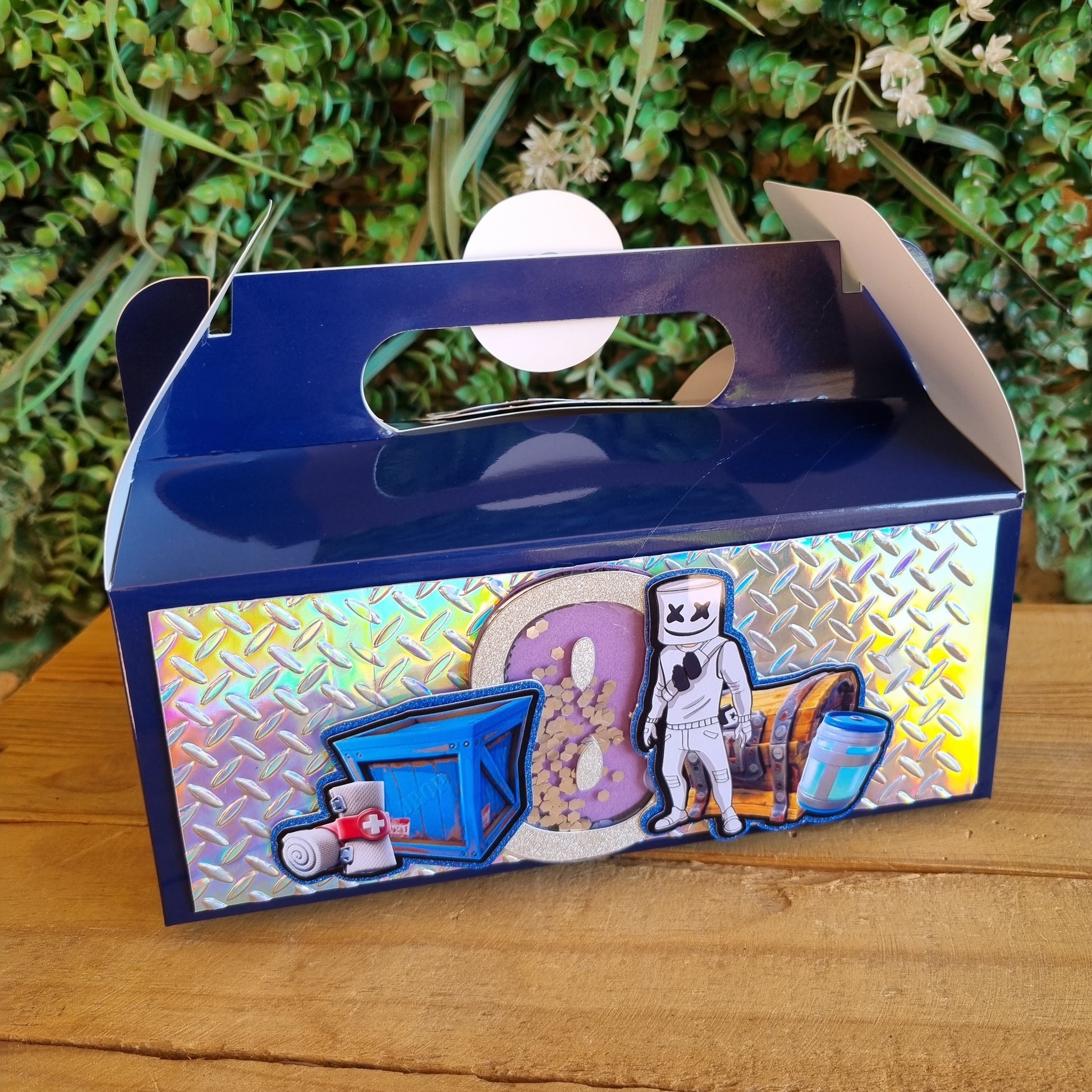 Decorative box with colorful design on a wooden surface and green plants