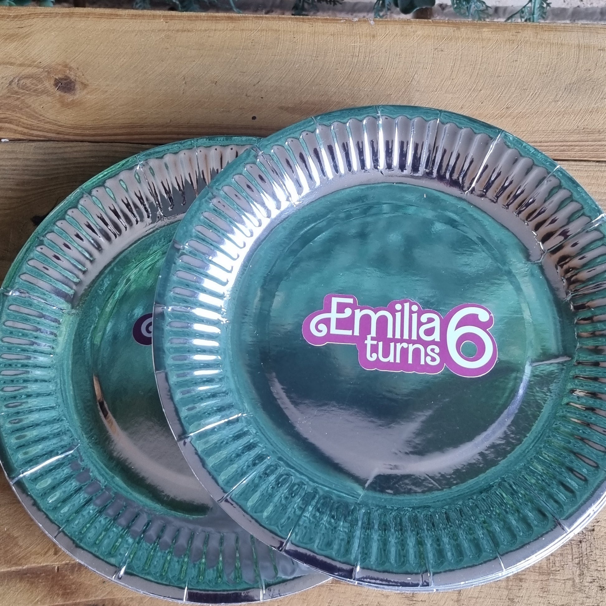 Teal and clear Emilia & Co. product on a wooden surface with greenery.