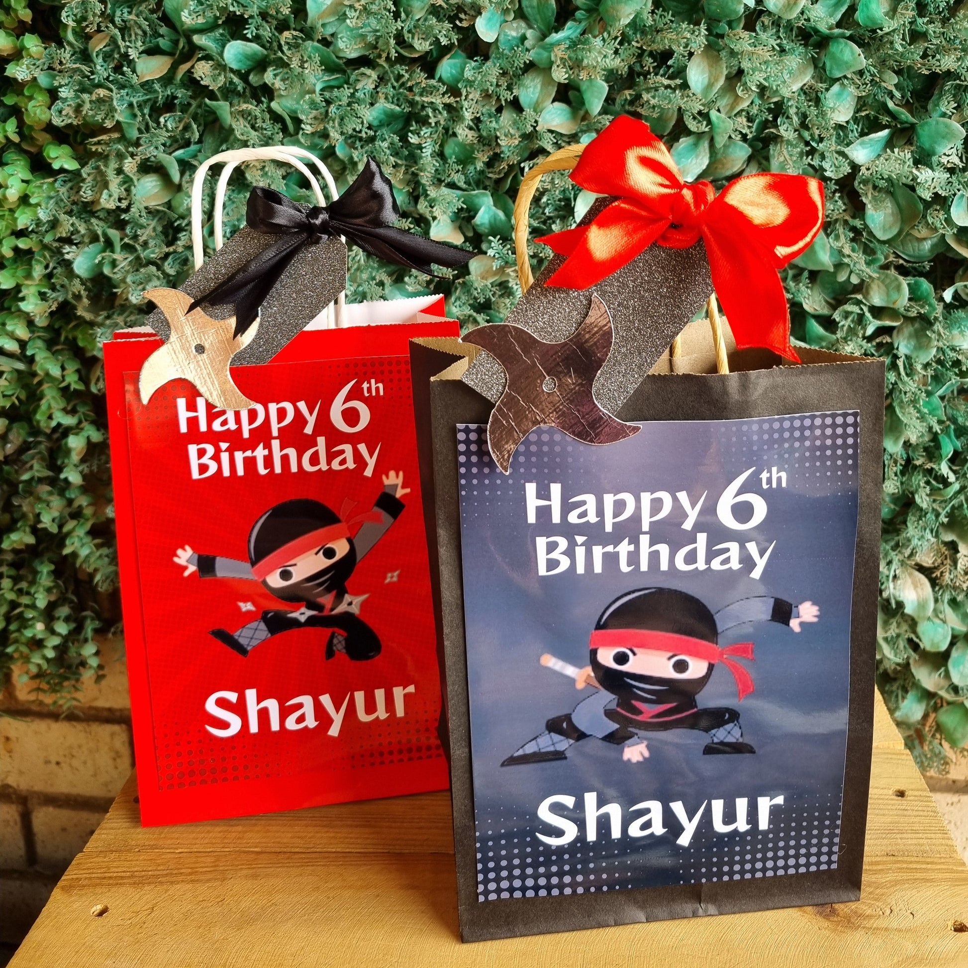 Two party favor bags with 'Happy 6th Birthday Shayur' text on a green textured background.