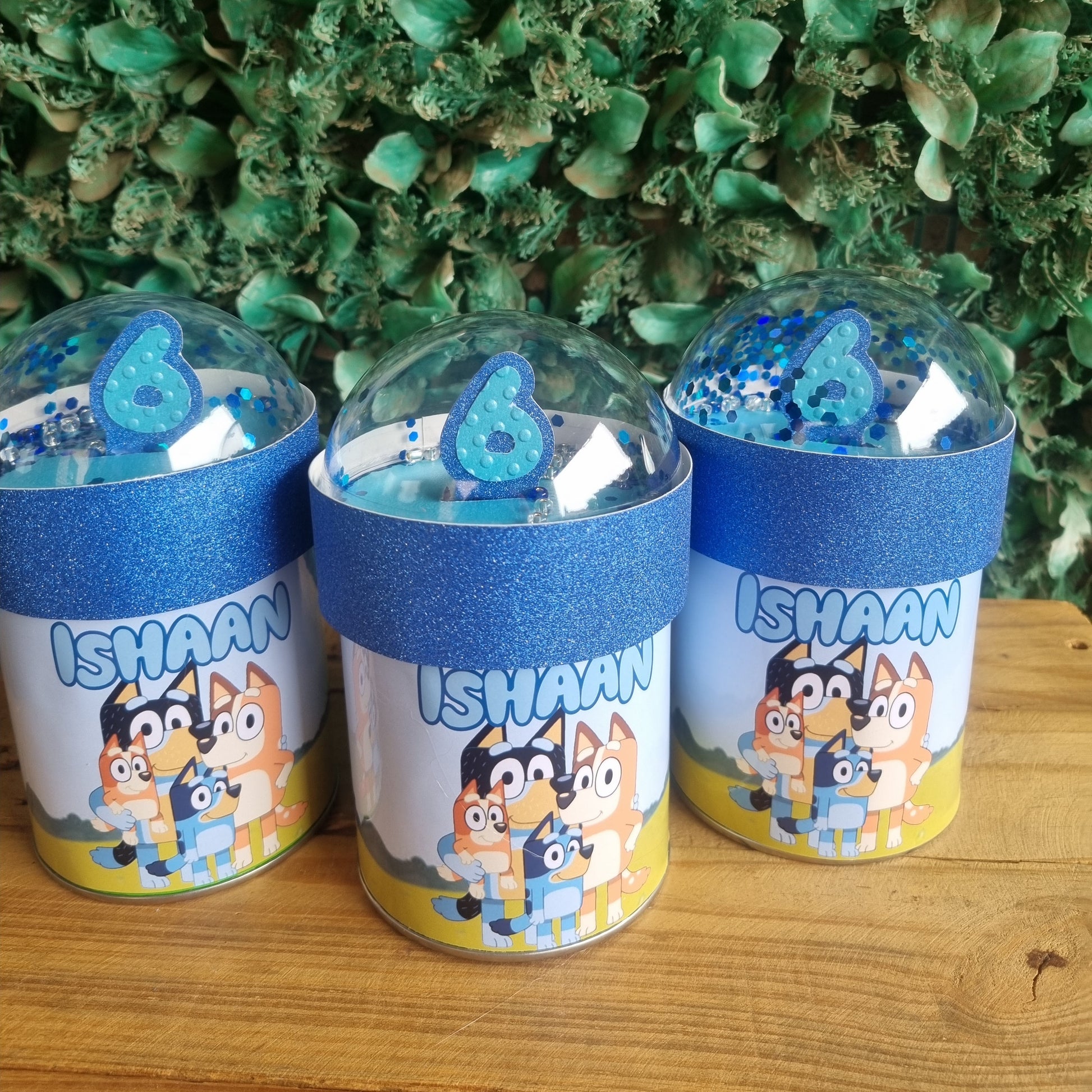 Three small cylindrical containers with colorful labels on a wooden surface.