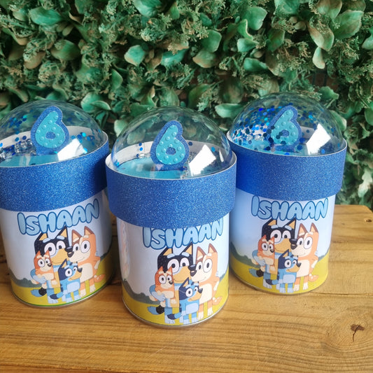 Three small cylindrical containers with colorful labels on a wooden surface.