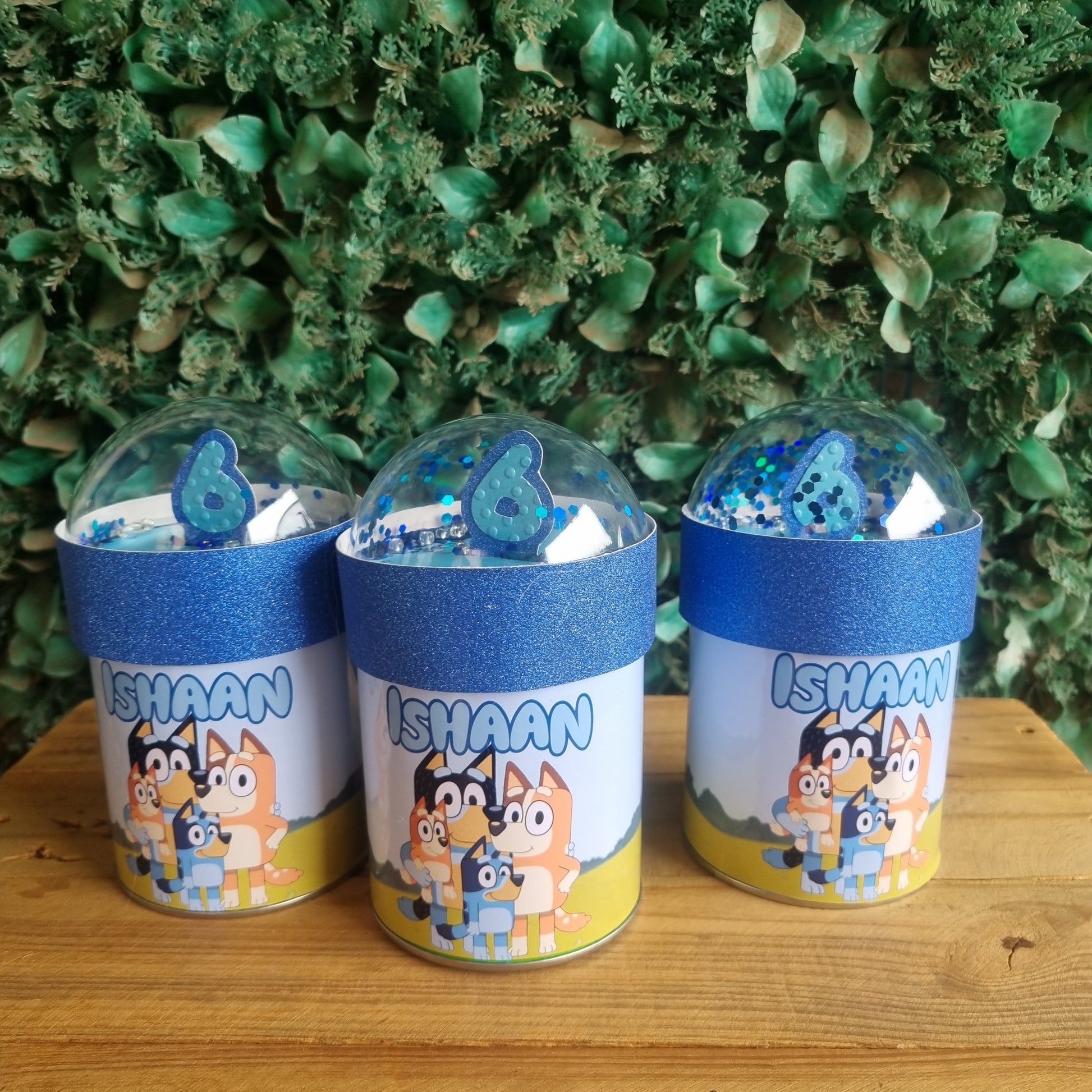 Three small bottles with colorful labels on a wooden surface and green textured background