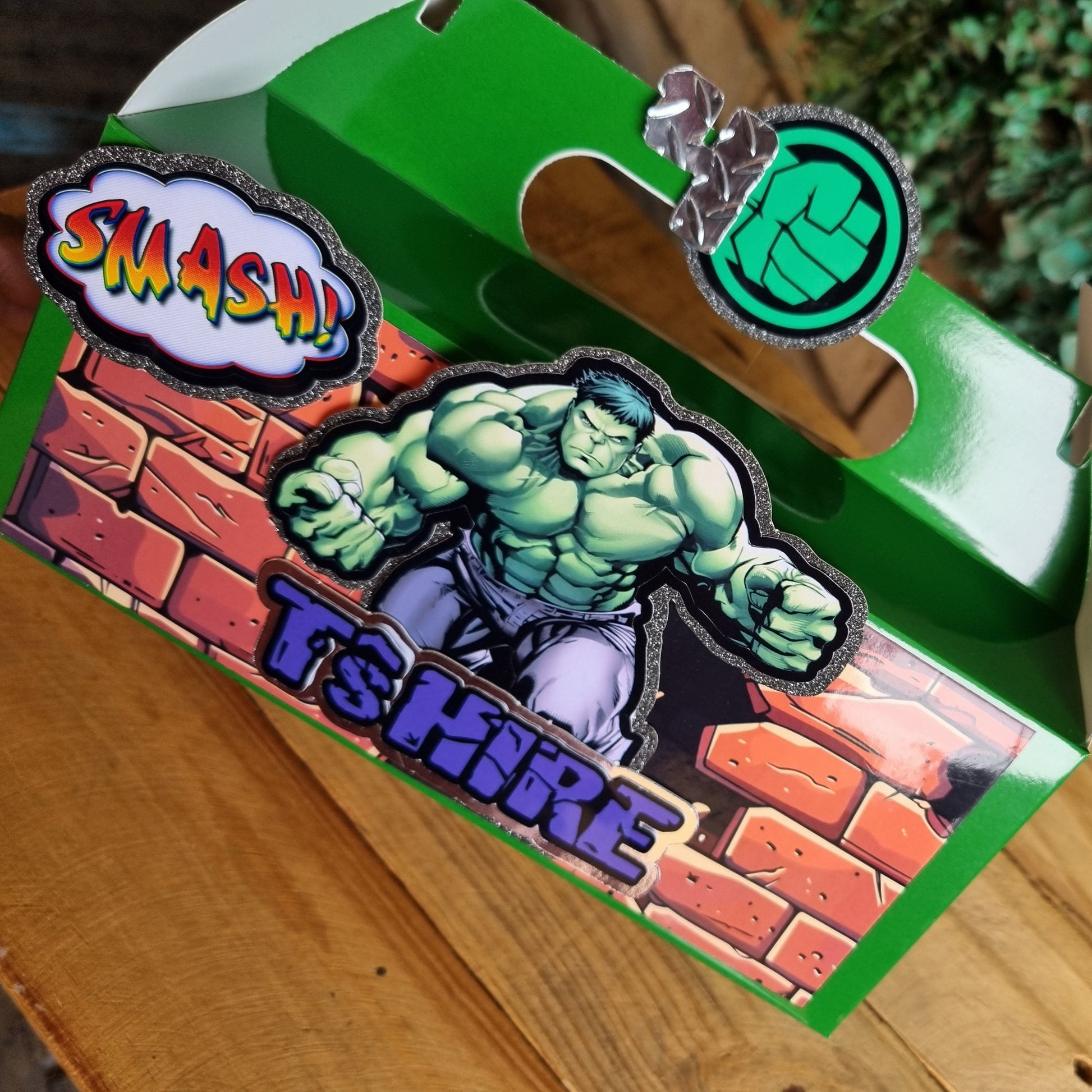 Green superhero-themed box with character design on a wooden surface