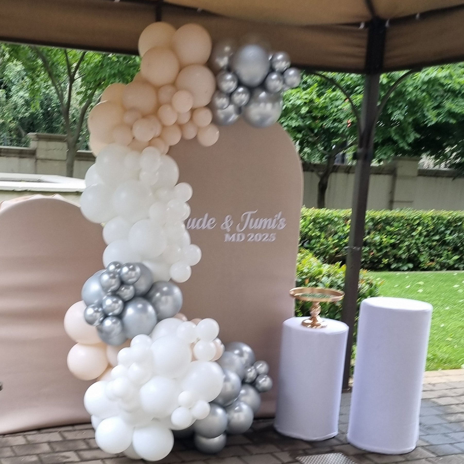 Decorative arch with balloons on a paved outdoor area
