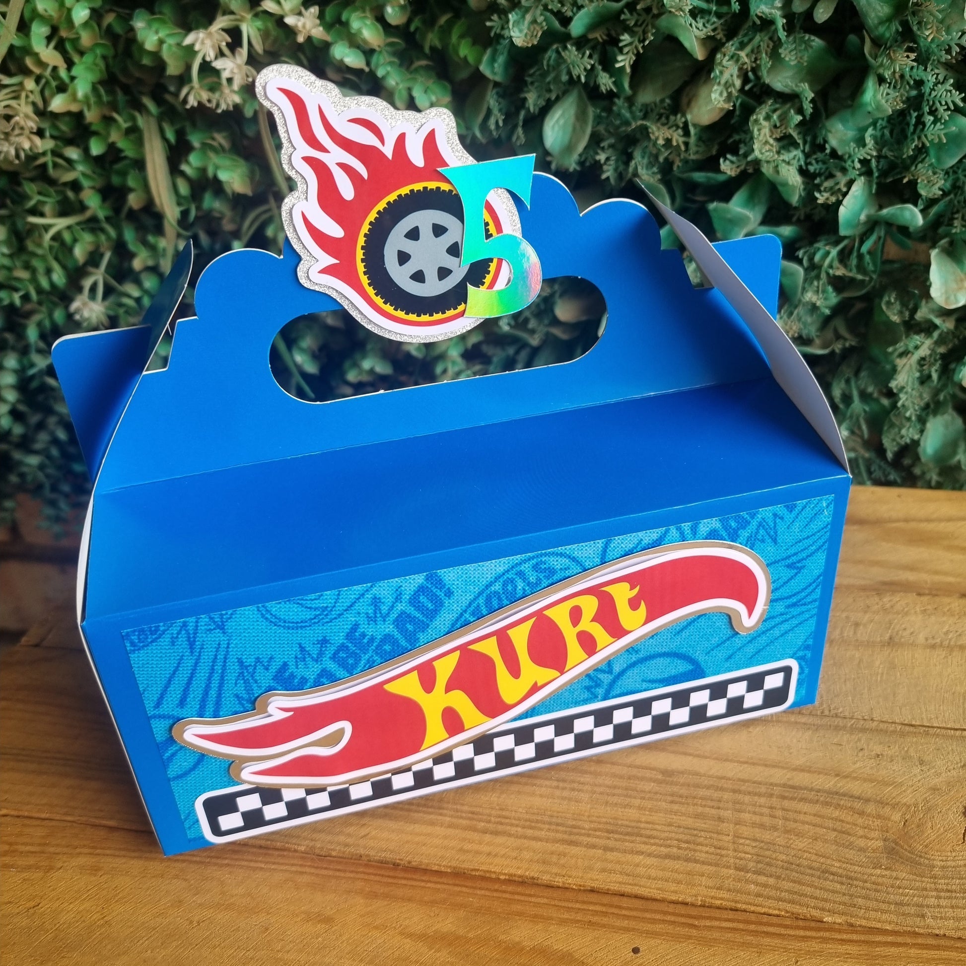 Blue toy car box with 'Hot Wheels' branding on a wooden surface.